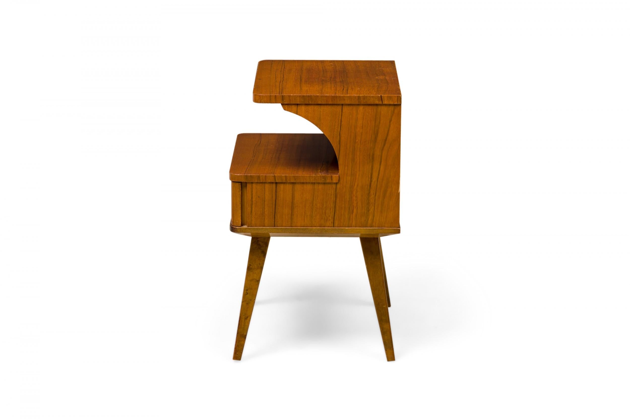 Pair of Mid-Century American (1950s) 2-tiered walnut nightstands with curved, overhanging tops, rounded corners and splayed, tapered legs. (ERNO FABRY) (PRICED AS Pair)

Wear to finish, some losses.