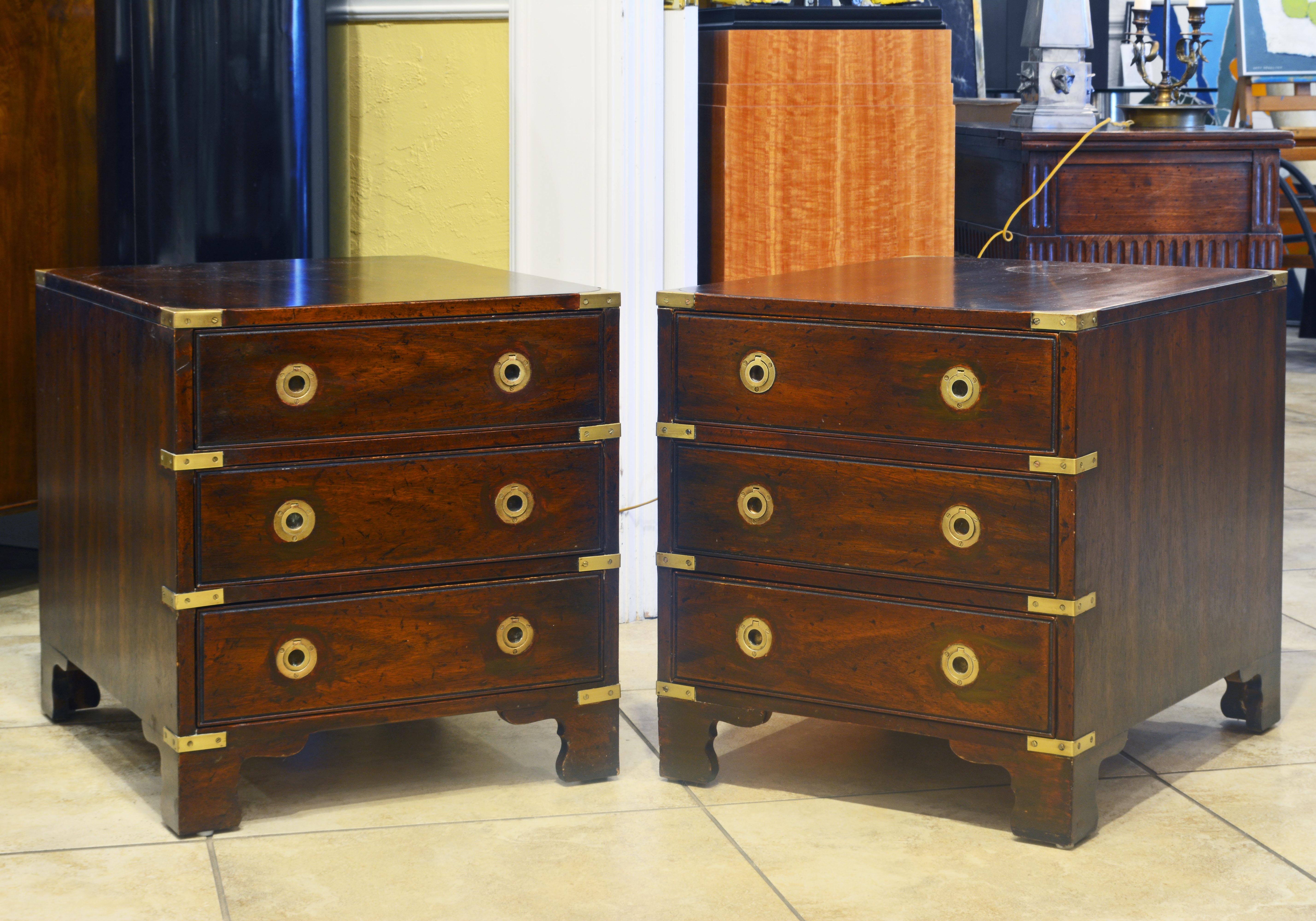 Dating to circa 1970 this pair of small Campaign style chest of drawers are great as either end tables or nightstands. The wood has a deep warm color contrasting well to the polished brass mounts. They are branded 'Heritage'.