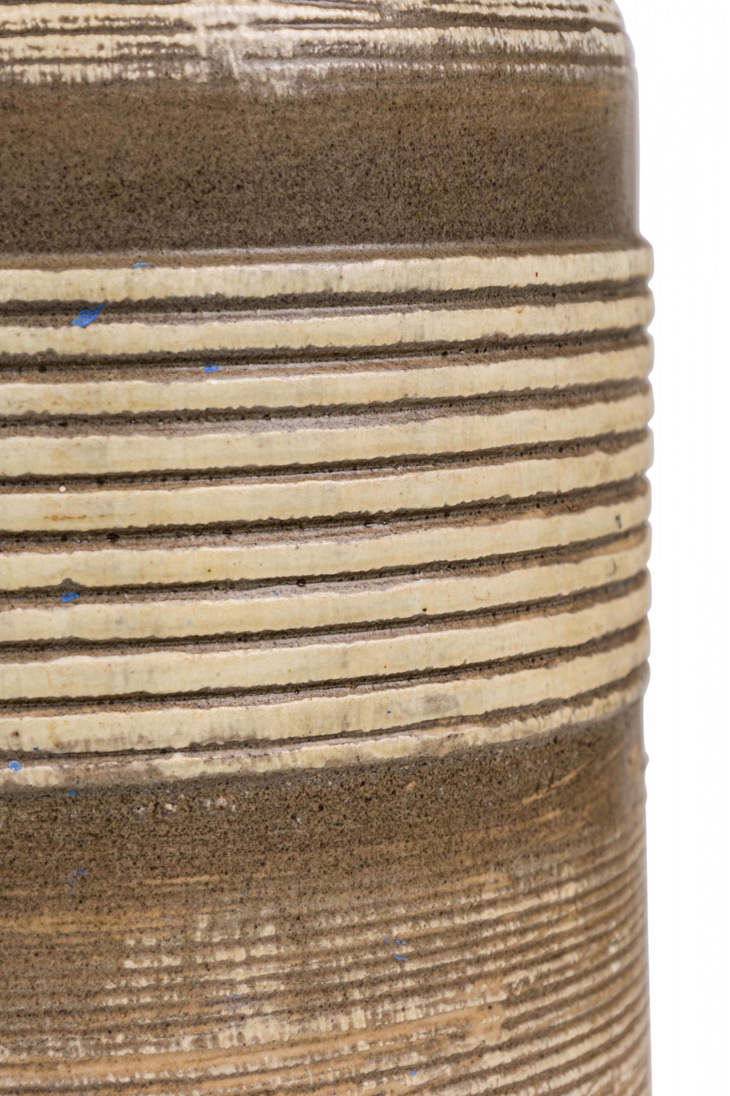 Paire de lampes de table en céramique américaine du milieu du siècle, en forme de tonneau à bande texturée avec des épaules arrondies aplaties se rétrécissant vers des cols cylindriques qui abritent des tiges en laiton, toutes deux avec des prises