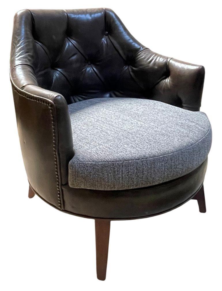 Une paire de fauteuils club élégants et modernes du milieu du siècle, avec des dossiers et des accoudoirs en cuir brun fumé profondément touffeté, associés à des coussins d'assise gris rembourrés. La silhouette arrondie en forme de tonneau offre un