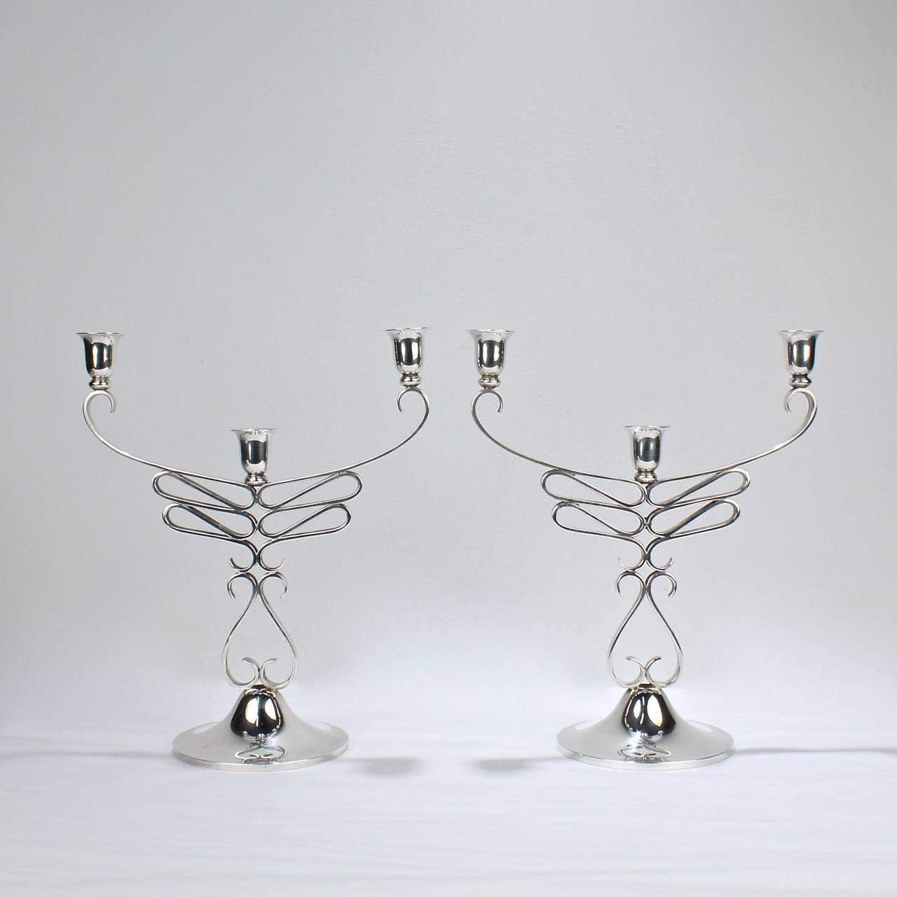 An amazing pair of Mid-Century Modernist sterling silver candelabra by Alfredo Sciarrotta. 

This impressive pair rests squarely among the best of Sciarrotta designs. 

Each candelabrum has three lights supported by a folded, tapering loop body