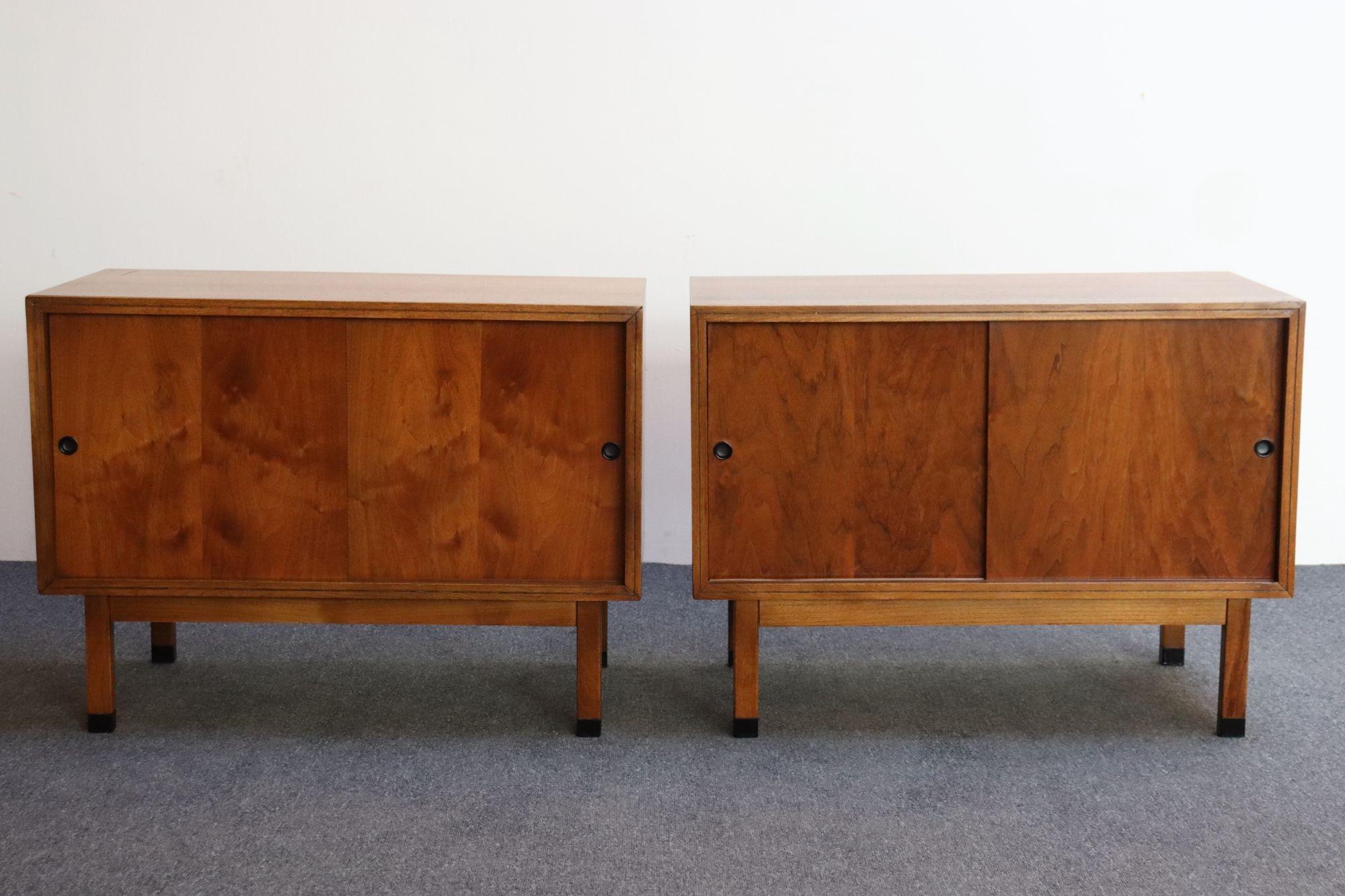 Pair of Mid-Century Modern walnut record cabinets by Lane (ca. 1960s, USA).
Composed of sliding doors with black recessed metal pulls and corresponding black feet opening to reveal two fixed LP dividers/side (four dividers/cabinet).
Stylish,