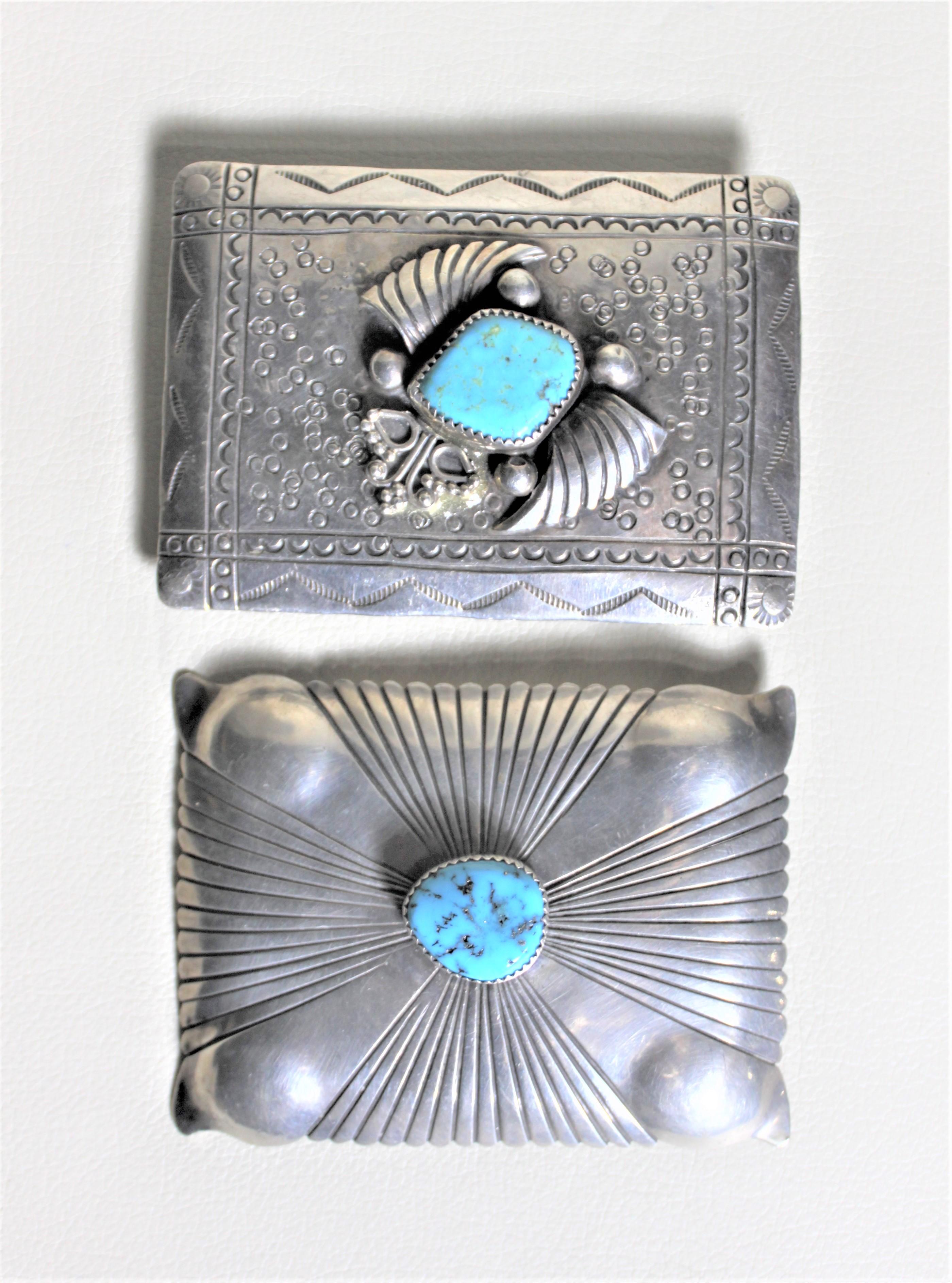 This pair of midcentury silver and turquoise belt buckles are presumed to have been made in the United States in approximately 1965. The buckle pictured in the top features a central inlaid turquoise stone surrounded by metal work resembling