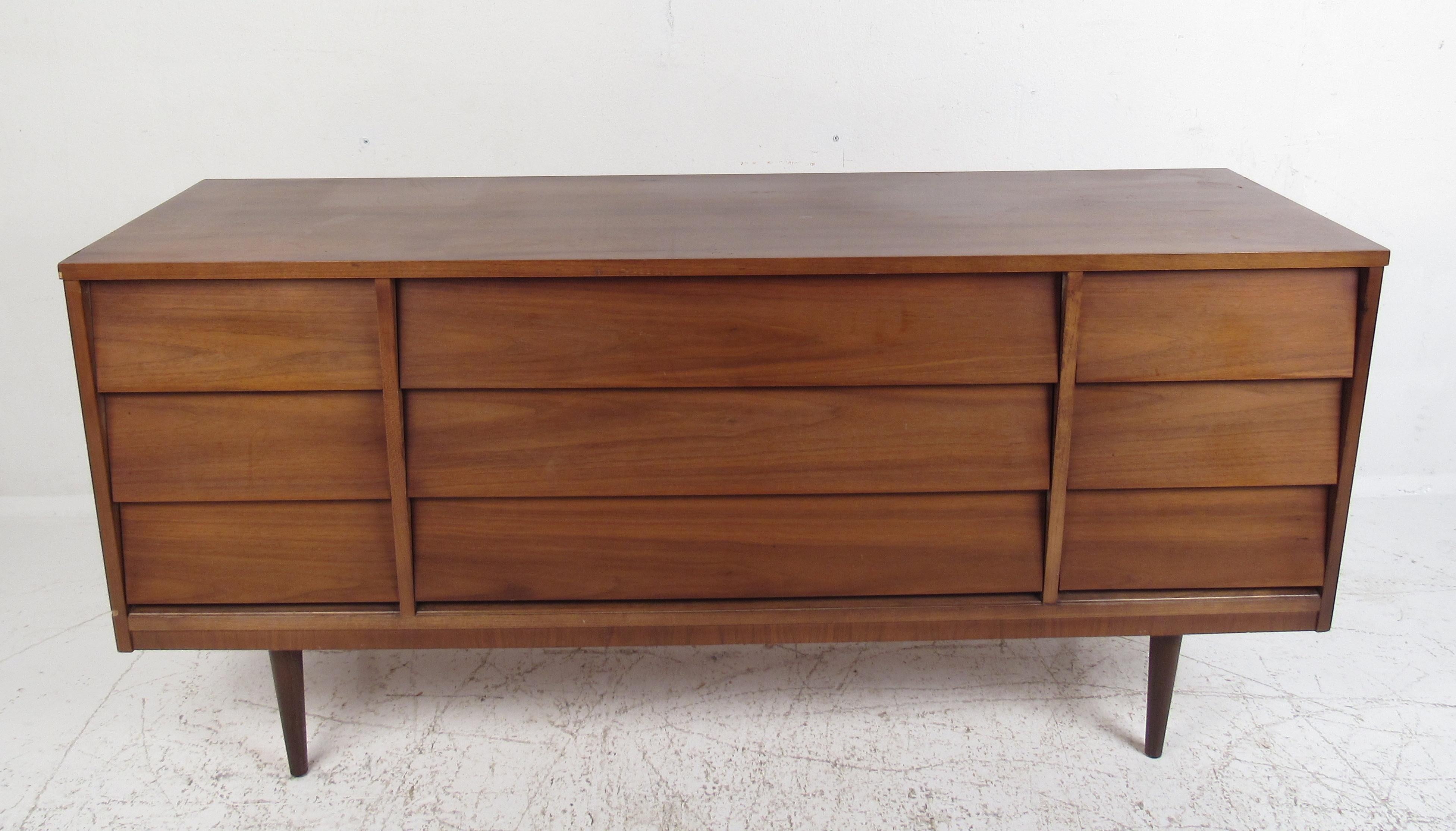 This beautiful pair of vintage modern dressers offer plenty of room for storage within their many drawers. A simple, yet stylish design with straight lines and a charming vintage walnut finish. The unusual hidden louvered drawer pulls and stubby