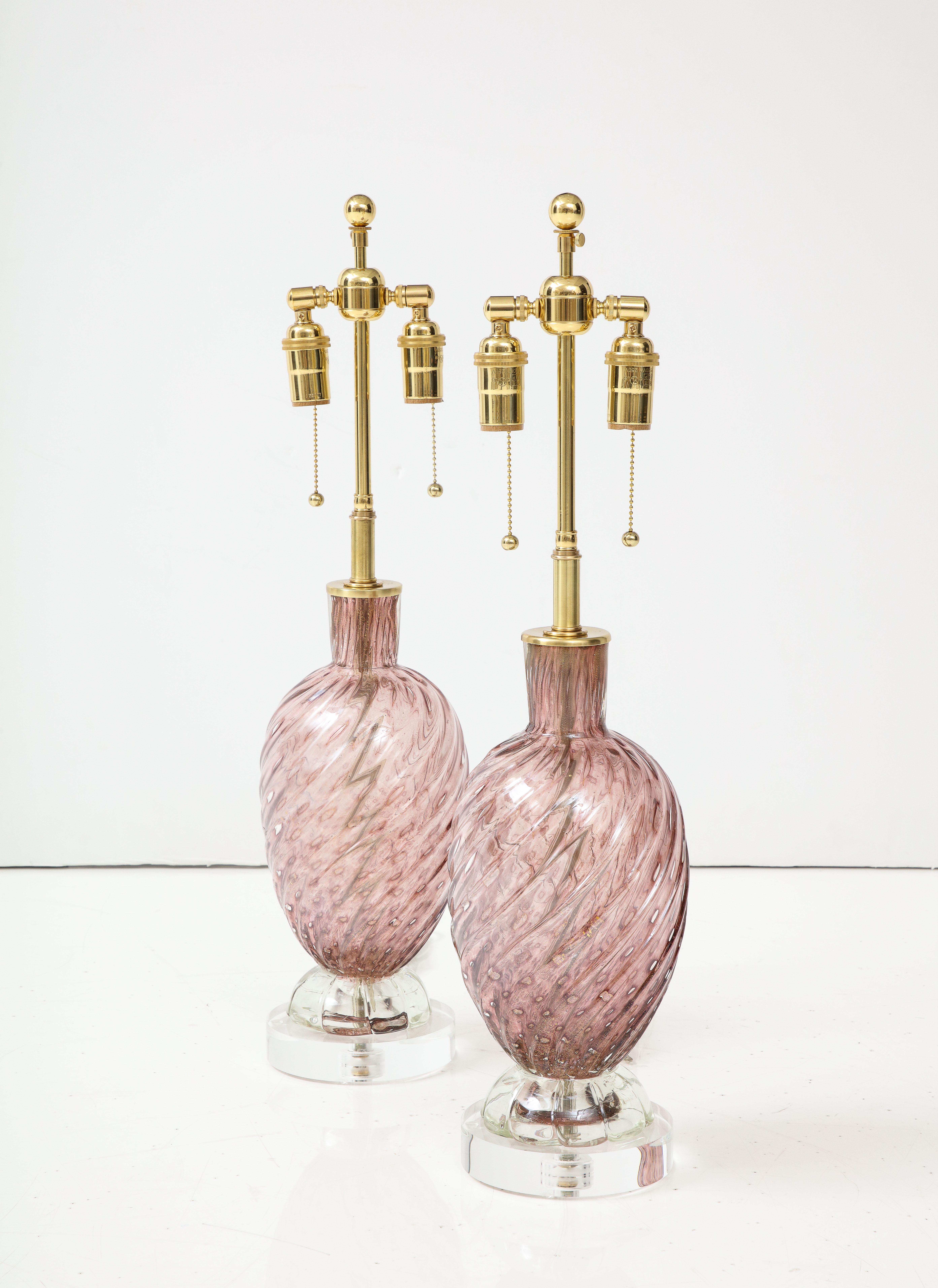 Pair of Amethyst colored Murano glass lamps with a swirled design and gold  dust inclusions. 
The lamps sit on thick lucite bases and they have been newly rewired with adjustable polished brass double clusters that take standard size light bulbs.
60