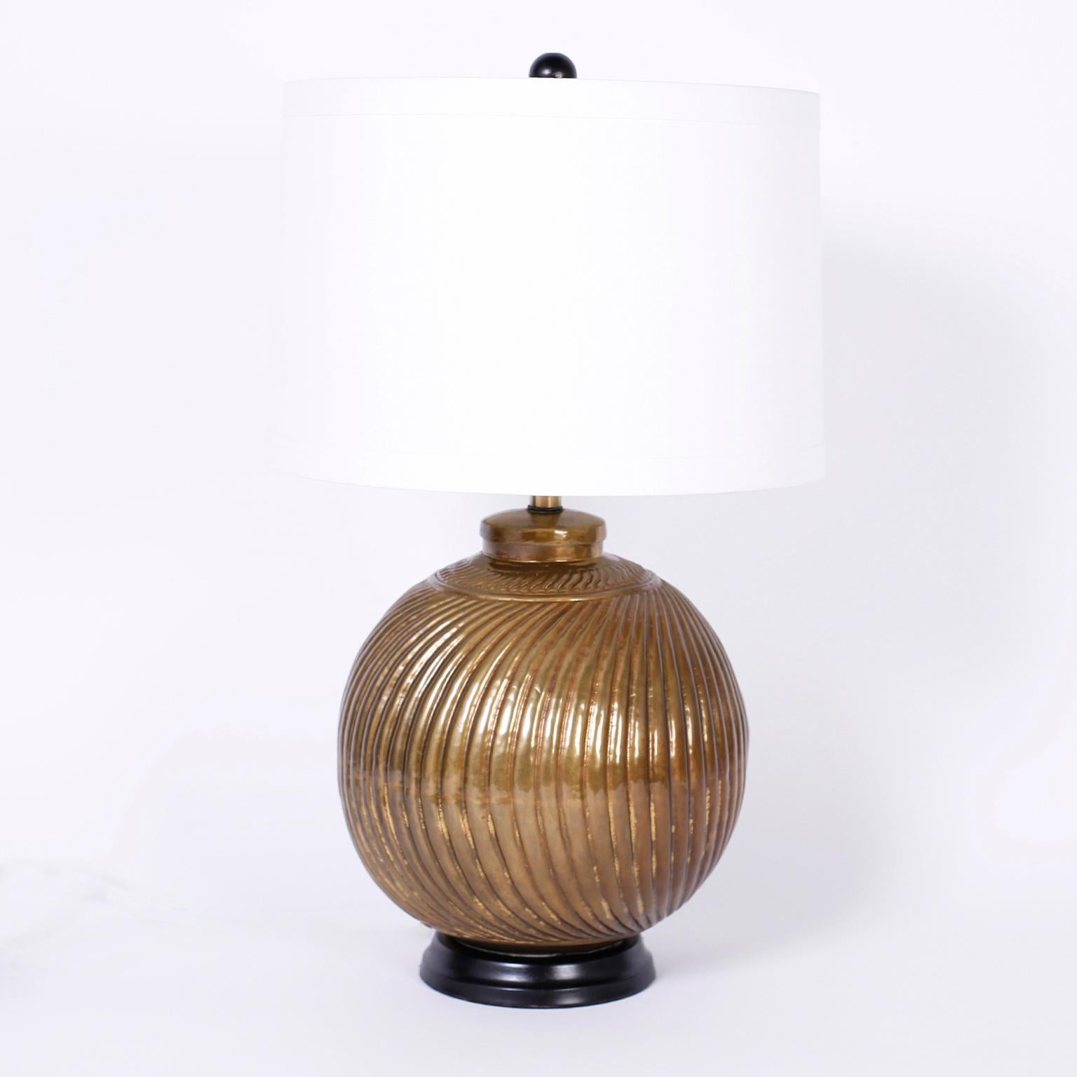 Pair of Anglo-Indian brass sphere table lamps with a hand-hammered ribbed pattern all around. Lacquered for easy care and presented on black lacquered wood turned bases.