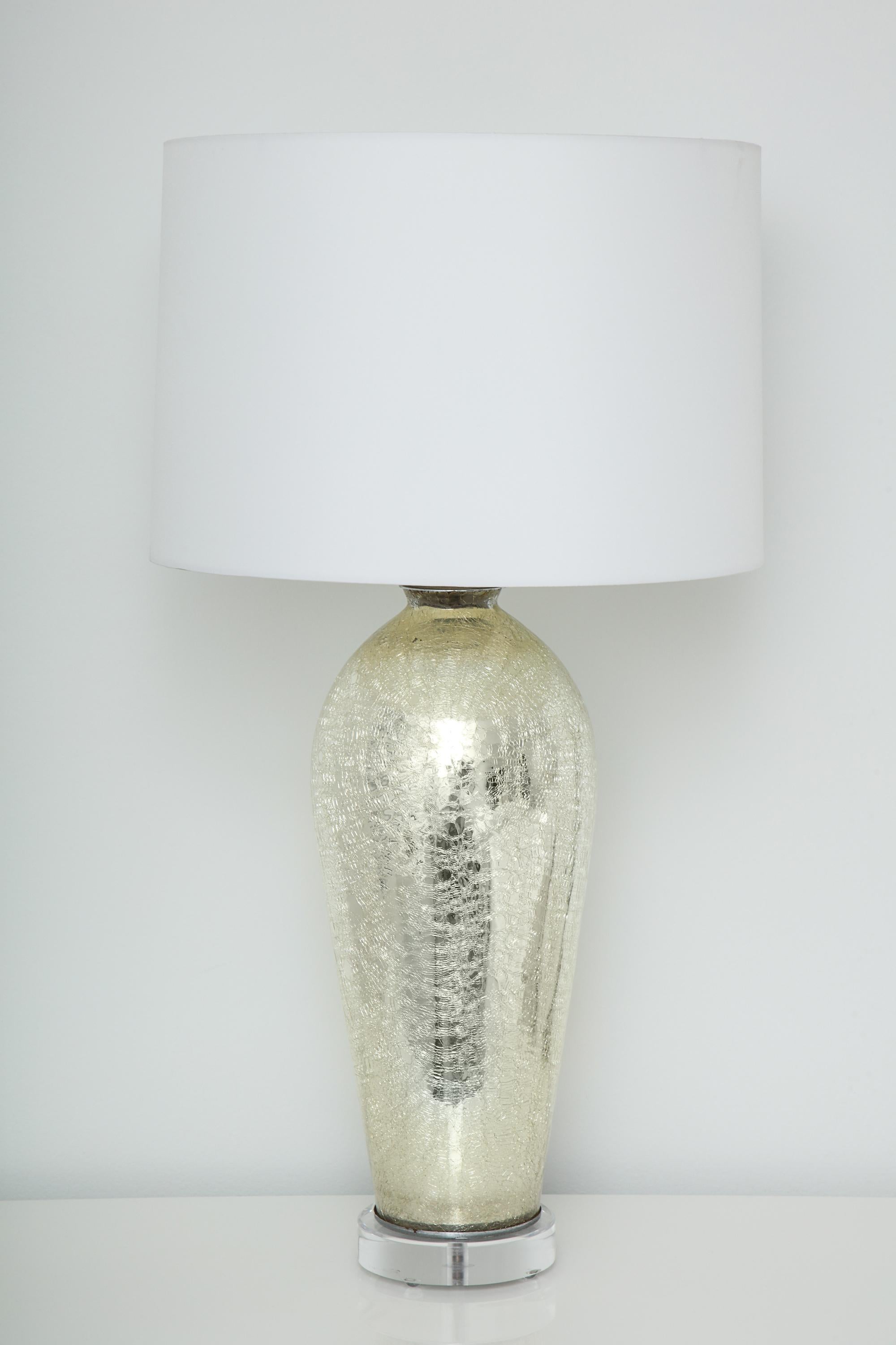 Each of ovoid form with mercury glass-like surface with antiqued craquelure; mounted on a Lucite base. Comes with shades. Height of base itself is 21.5