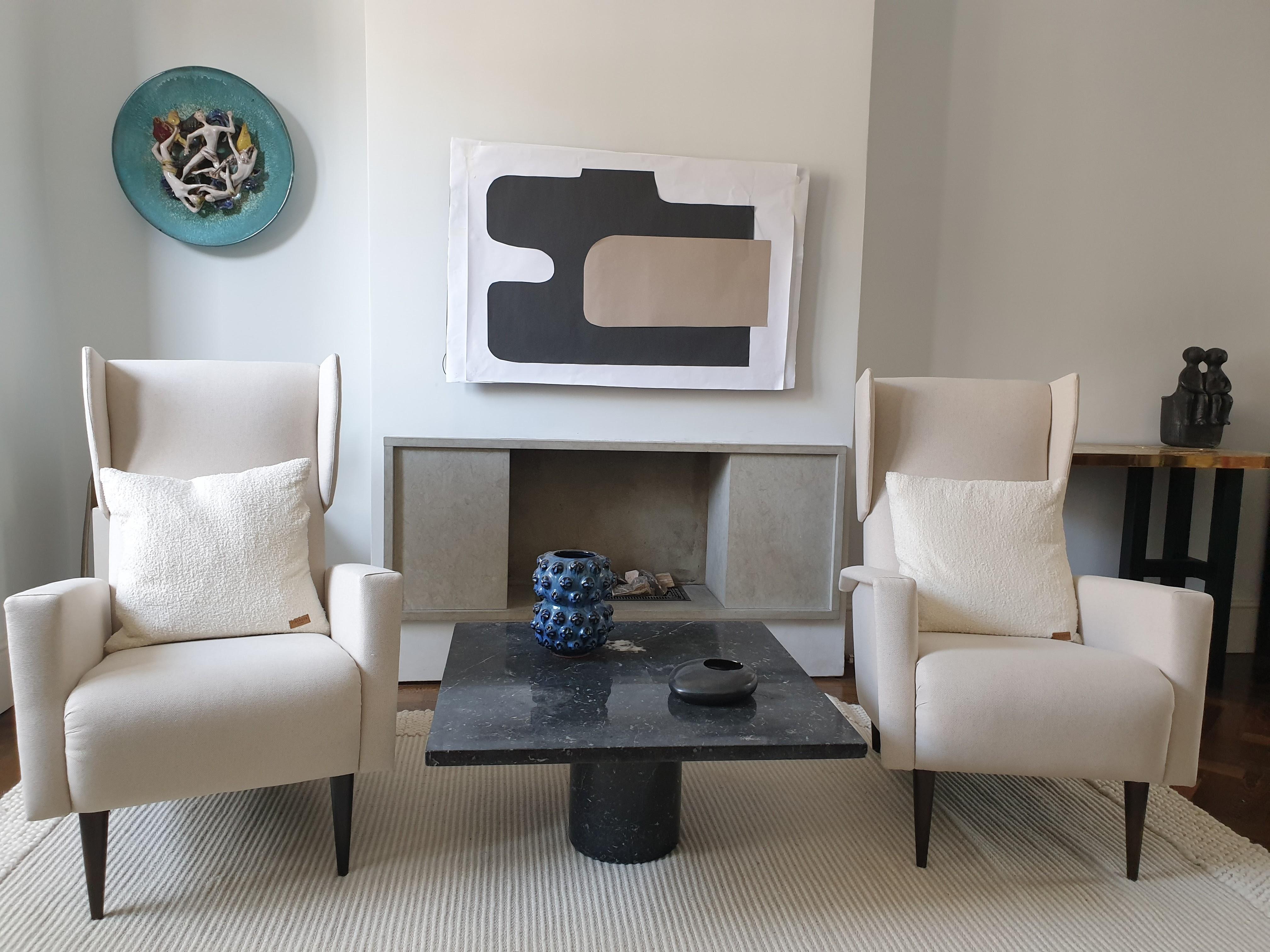 Pair of substantial wing chairs attributed to Gio Ponti. These armchairs have high backs with stylish wings and polished wooden legs. They have been reupholstered in off white linen. These well scaled chairs would grace both aperiod and more