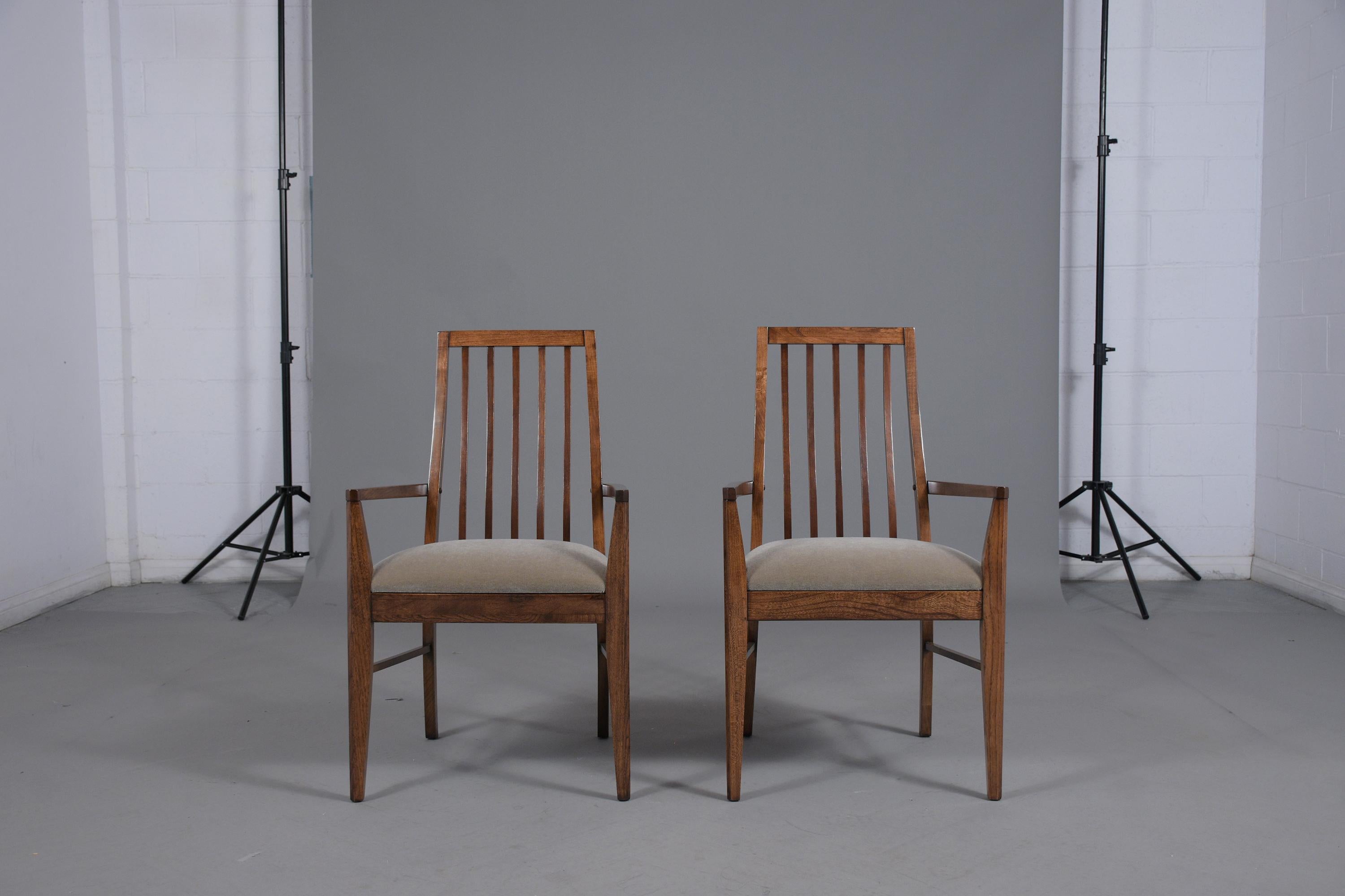 This vintage 1960s pair of mid-century modern armchairs are hand crafted out of walnut wood and have been restained with a newly lacquered finish and have been professionally restored by our expert craftsmen in house. The pair of lounge chairs have