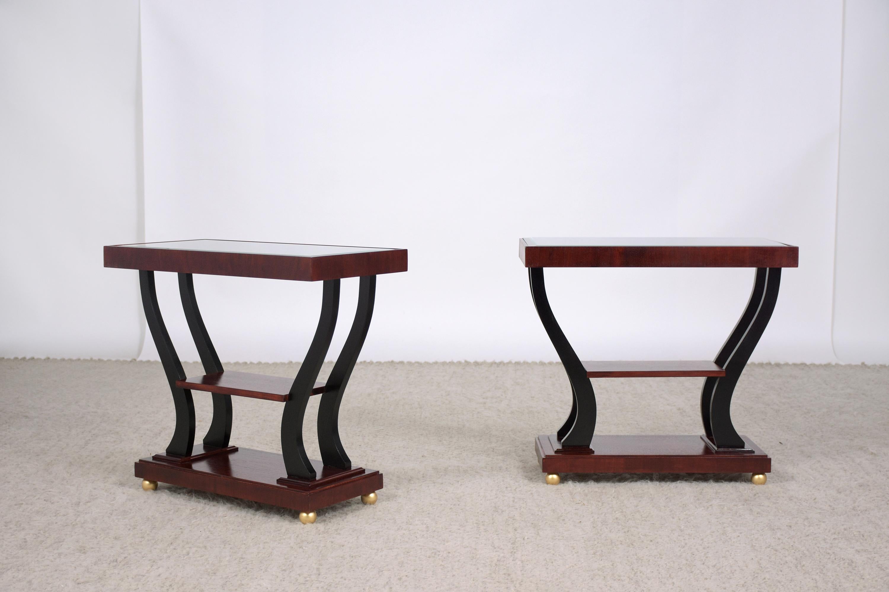 An extraordinary pair of 1950s art deco side tables in great condition hand-crafted out of walnut and completely restored by our craftsmen team. These fabulous pieces feature a rich walnut and ebonized color accents with lacquered finish, two tiers