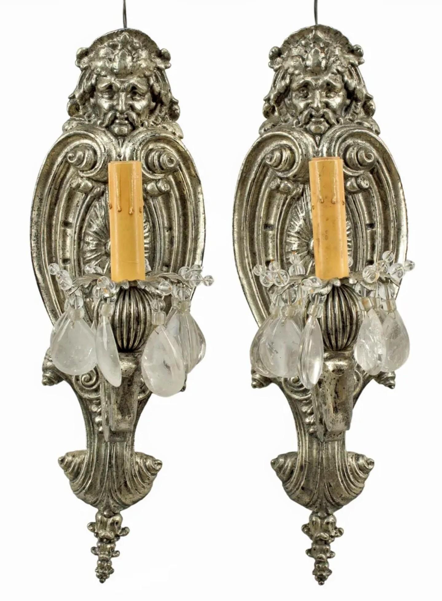 A stunning pair of European Baroque style silvered bronze one-light wall sconces, possibly attributed to Maison Bagues (French, 1860-), featuring sculptural figural scroll motif with single faux candle and rock crystal prisms. 

Dimensions: