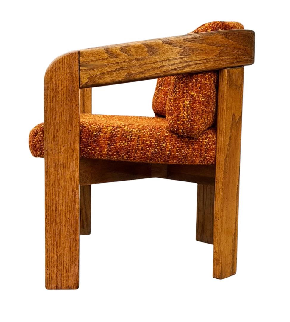 Pair of oak lounge chairs in the the style of Lou Hodges. The chairs feature solid oak framing with original tweed fabric in very good condition. 