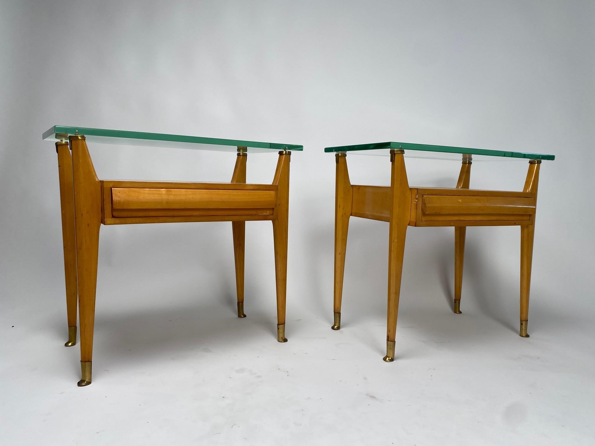 Refined pair of Italian bedside tables from the 1950s in wood, brass and thick glass on the top.

Pair of nightstands which are characterized by a thick glass plate on the top, probably made by the same glassworks that produced the glass for