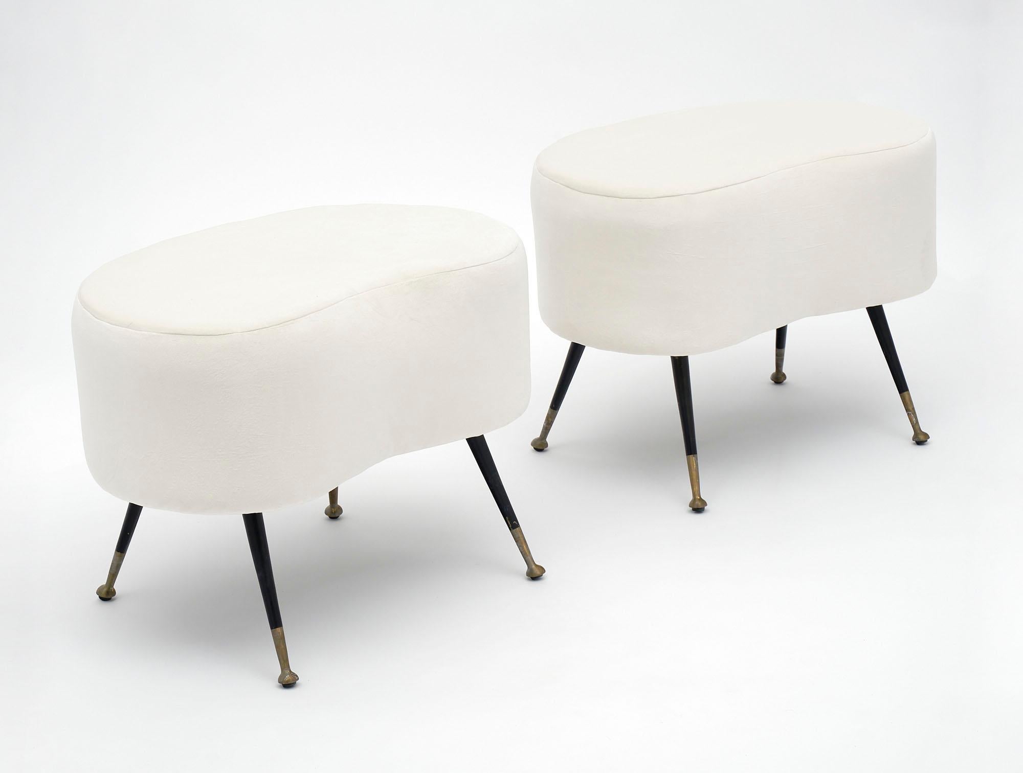 Pair of benches from Italy with black lacquered steel legs and brass feet. They have been newly upholstered in an ivory micro fiber.