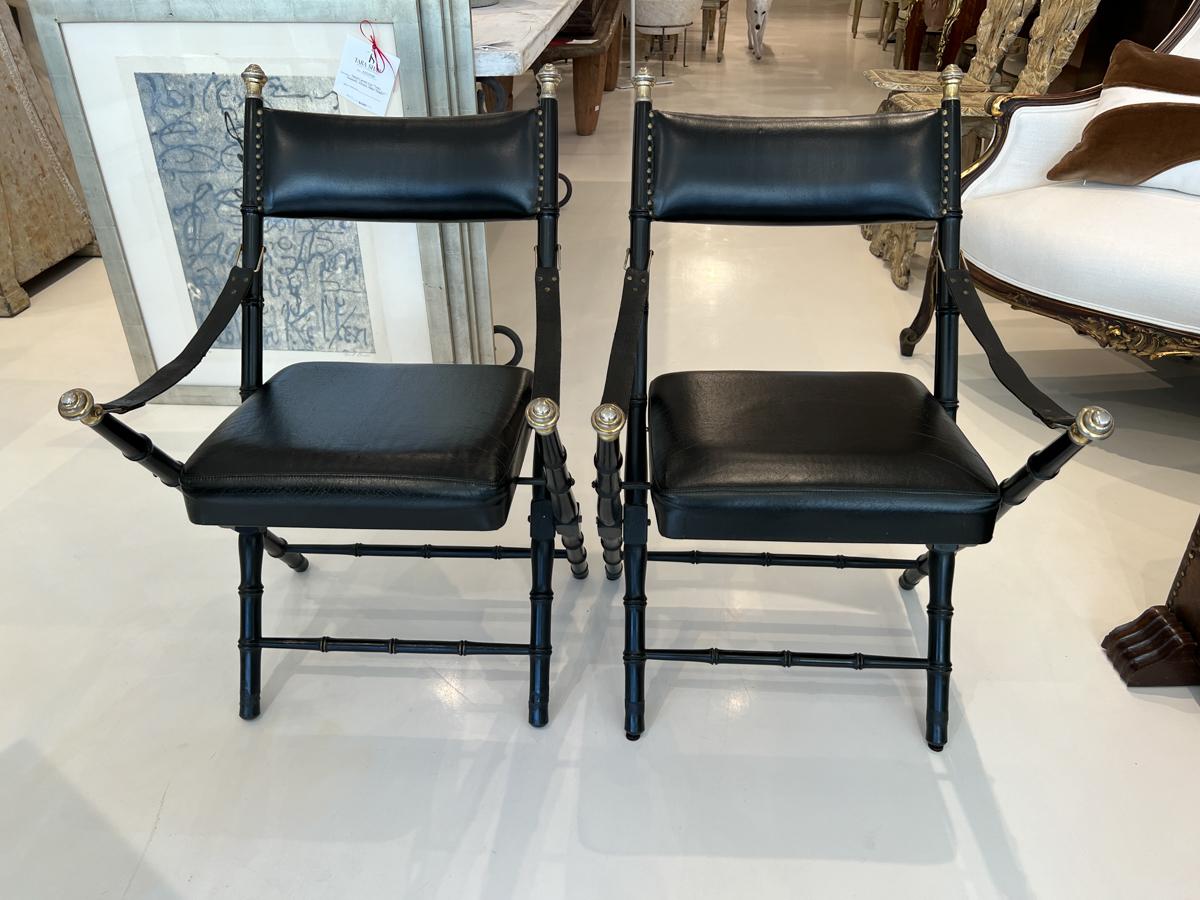 Beautiful style that almost resembles a folding chair. Black leather in excellent condition. The wood stretchers have a bamboo motif and top and chair arms finished with brass knobs.
There are two sets of two available.