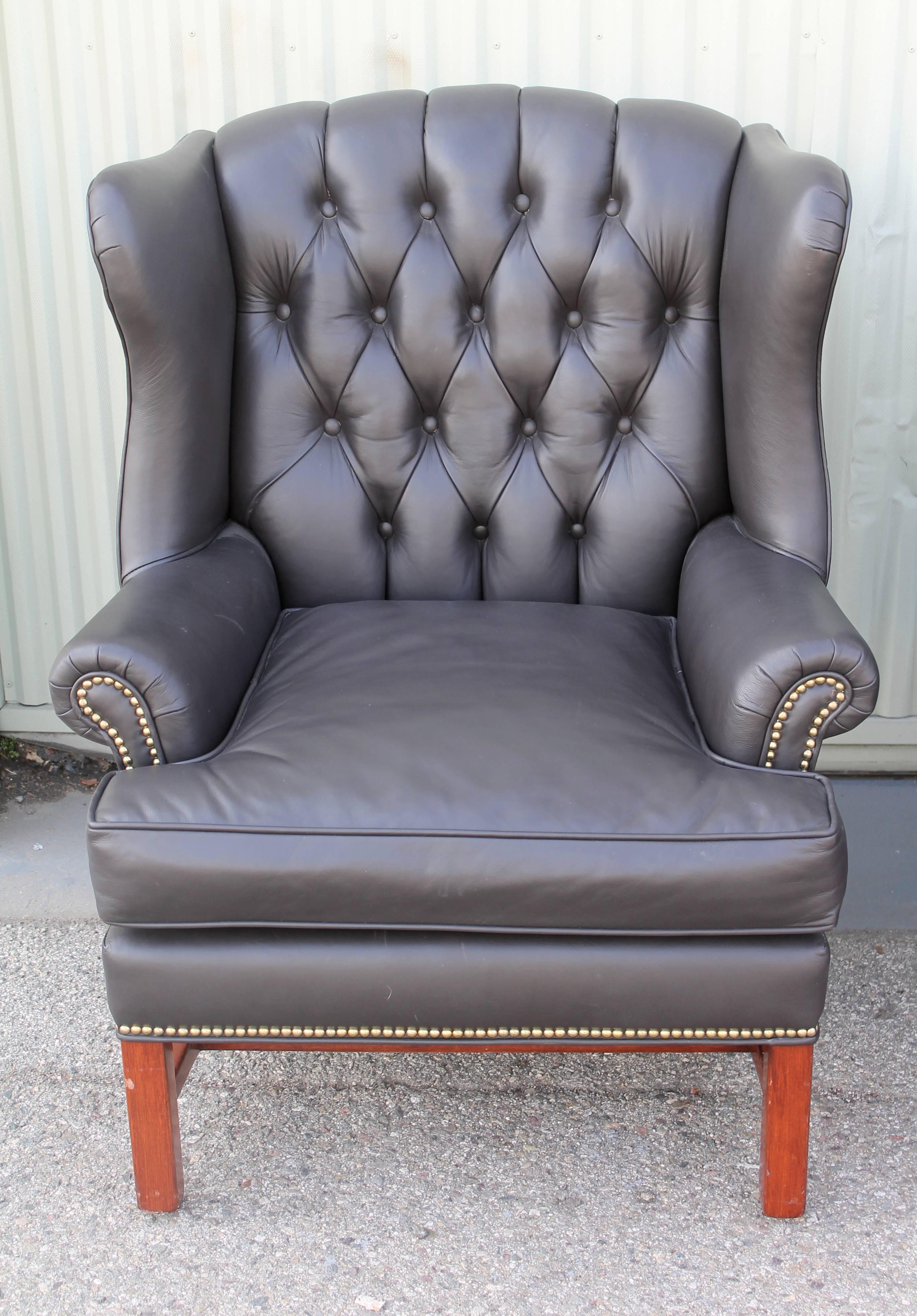 This fine pair of recovered soft Italian leather wing chairs are in fine condition. The brass studded trim raps around the entire chair. The chairs have the original makes label 