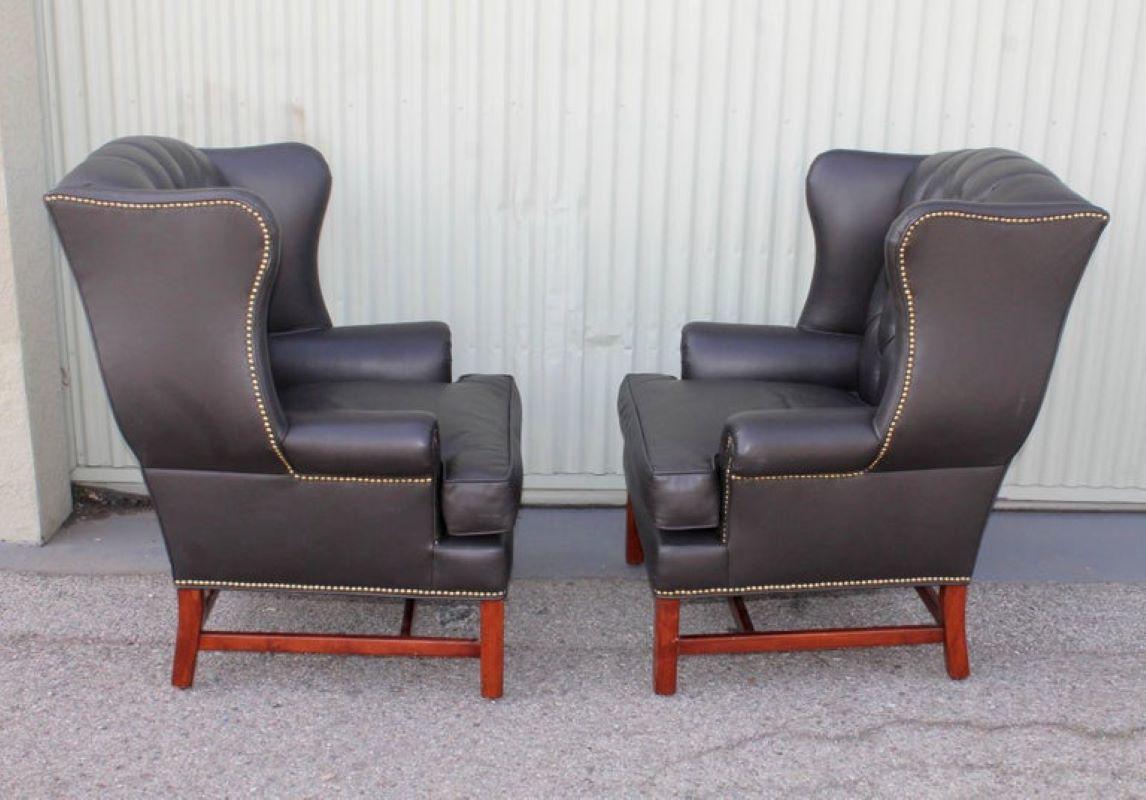This fine pair of recovered soft Italian leather wing chairs are in fine condition. 
The brass studded trim wraps around the entire chair. The chairs have the original makes label 