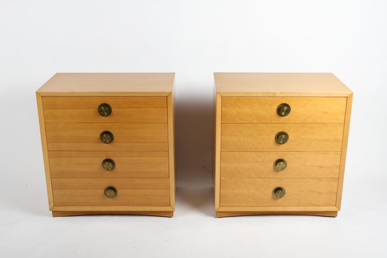 Nice pair of Mid-Century Modern bleached mahogany four drawer bachelors chests with round brass disc hardware on concave base. These would also make great nightstands or bedside chests due to their smaller scale. Original finish does show minor