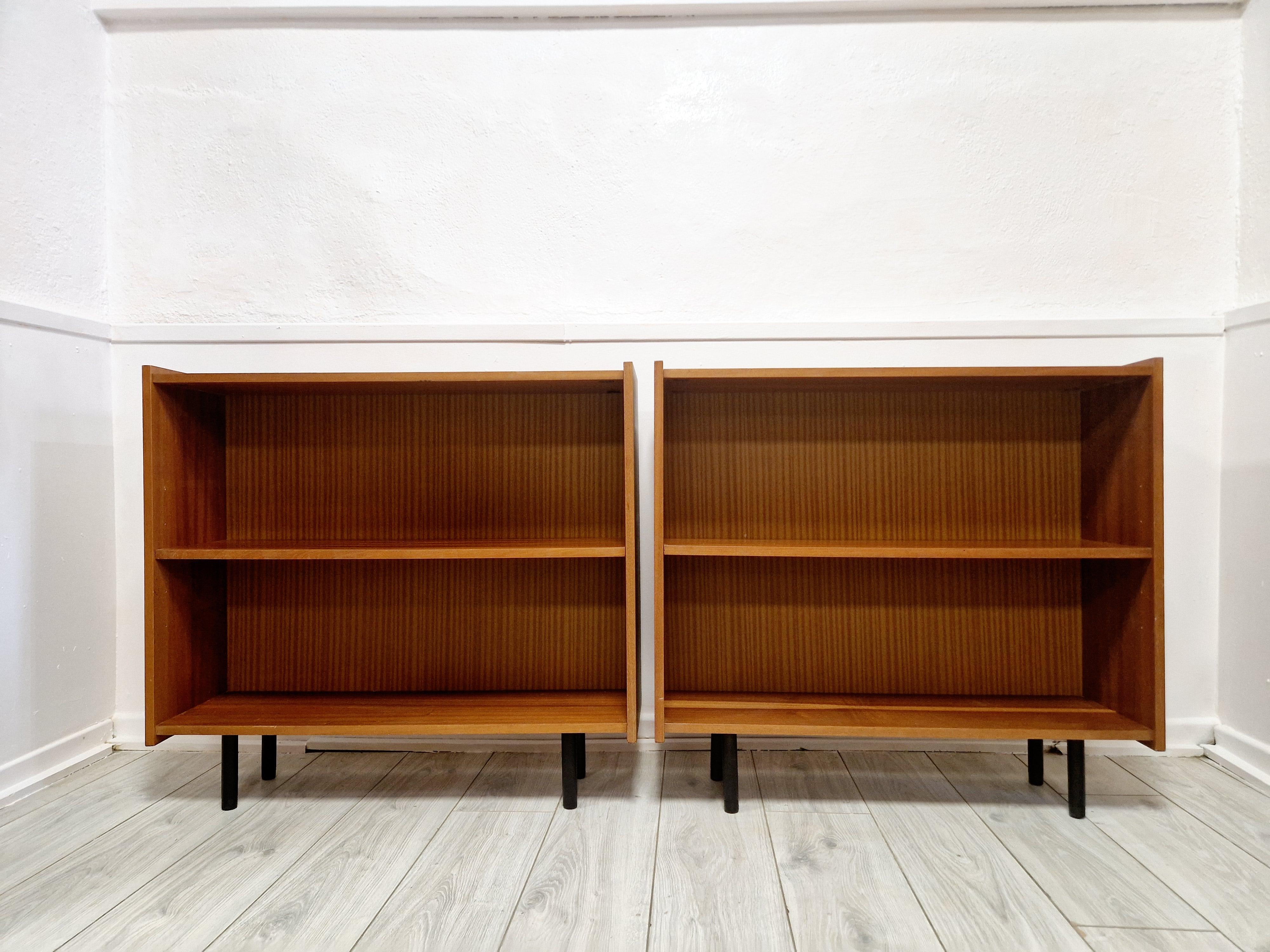 Dieses Paar Bücherregale aus Teakholzfurnier versprüht den Charme der Moderne aus der Mitte des Jahrhunderts und verleiht jedem Raum eine zeitlose Ästhetik. Mit einer Höhe von 83 cm, einer Länge von 90 cm und einer Tiefe von 27 cm bietet jedes Stück