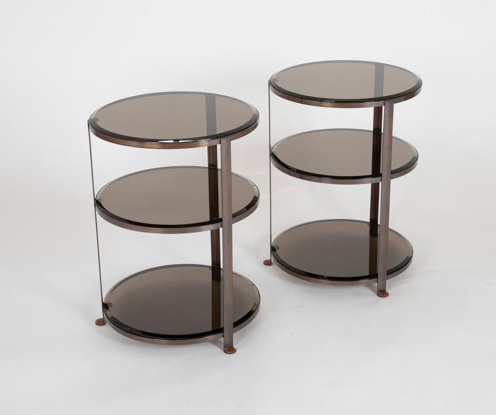 Pair of patinated brass three-tiered side table with tinted beveled glass and stitched leather feet. Beautiful modern design and bespoke craftmanship. Handsome and practical as side tables, end tables, or even stylish bedside tables.