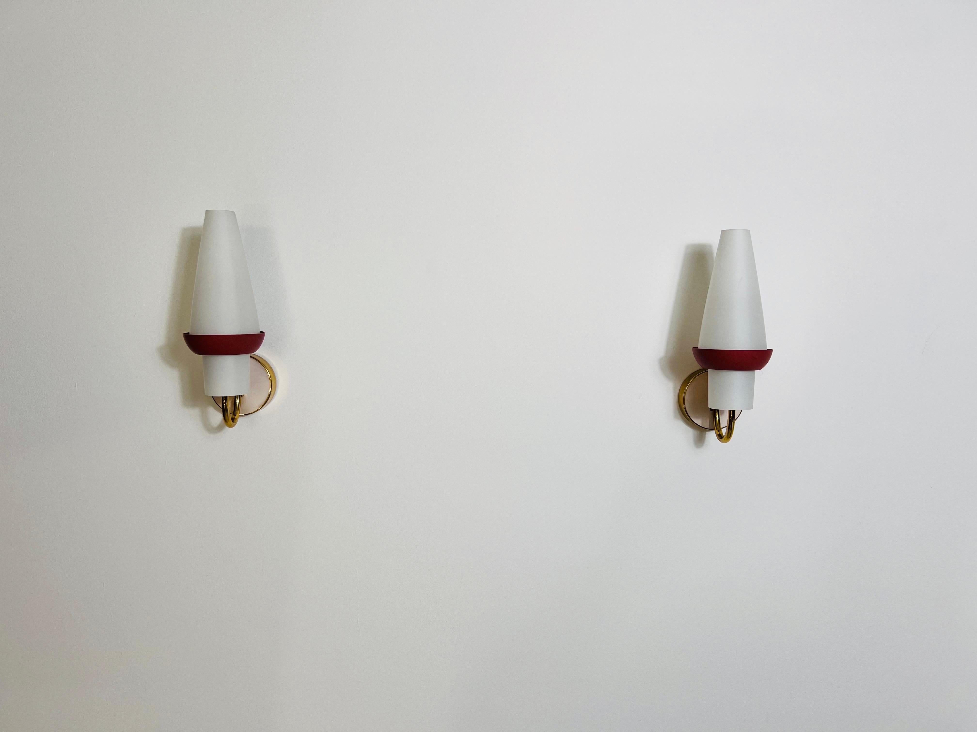 These stunning brass wall lamps, crafted in the 1960s, are designed in the distinctive style of Italian manufacturer Stilnovo. Featuring opal glass shades in a candle-like, conical shape, they exude mid-century elegance. The opal glass is set within