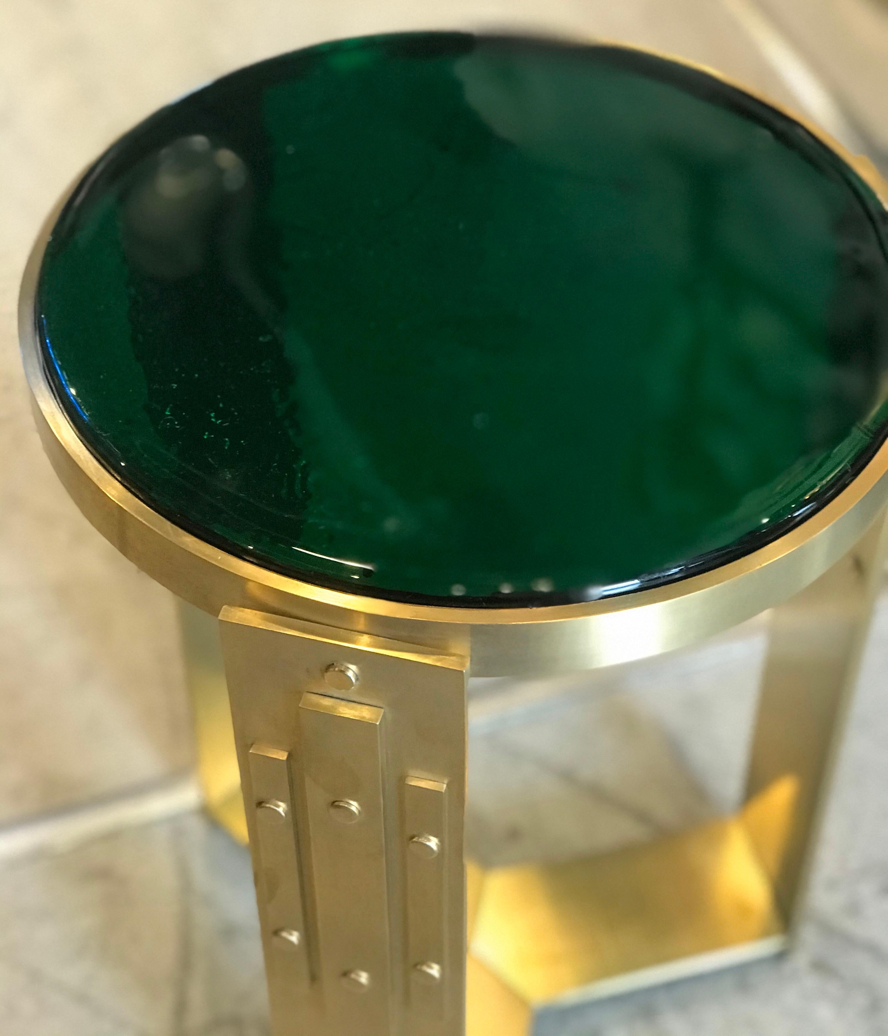 A pair of elegant brass accent tables with thick green blown glass table tops.