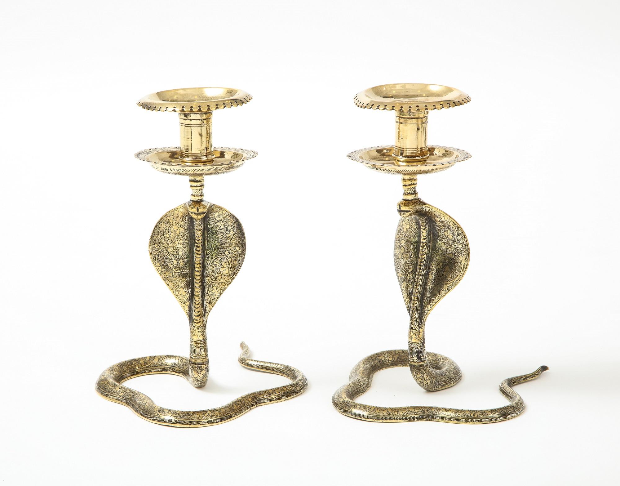 A brass pair of candelsticks each in the shape of a cobra. Cast brass has etched details on the length of the body and across the cup surface. Mid 20th Century.