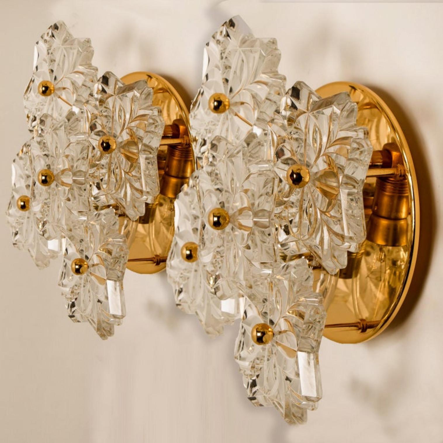 These sculptural wall sconces have the design of a bouquet of textured glass flowers and are from the historical lighting company Hillebrand. Each light has five glass shades. Flower shaped.

Each clear glass flower shade has textured petals and is