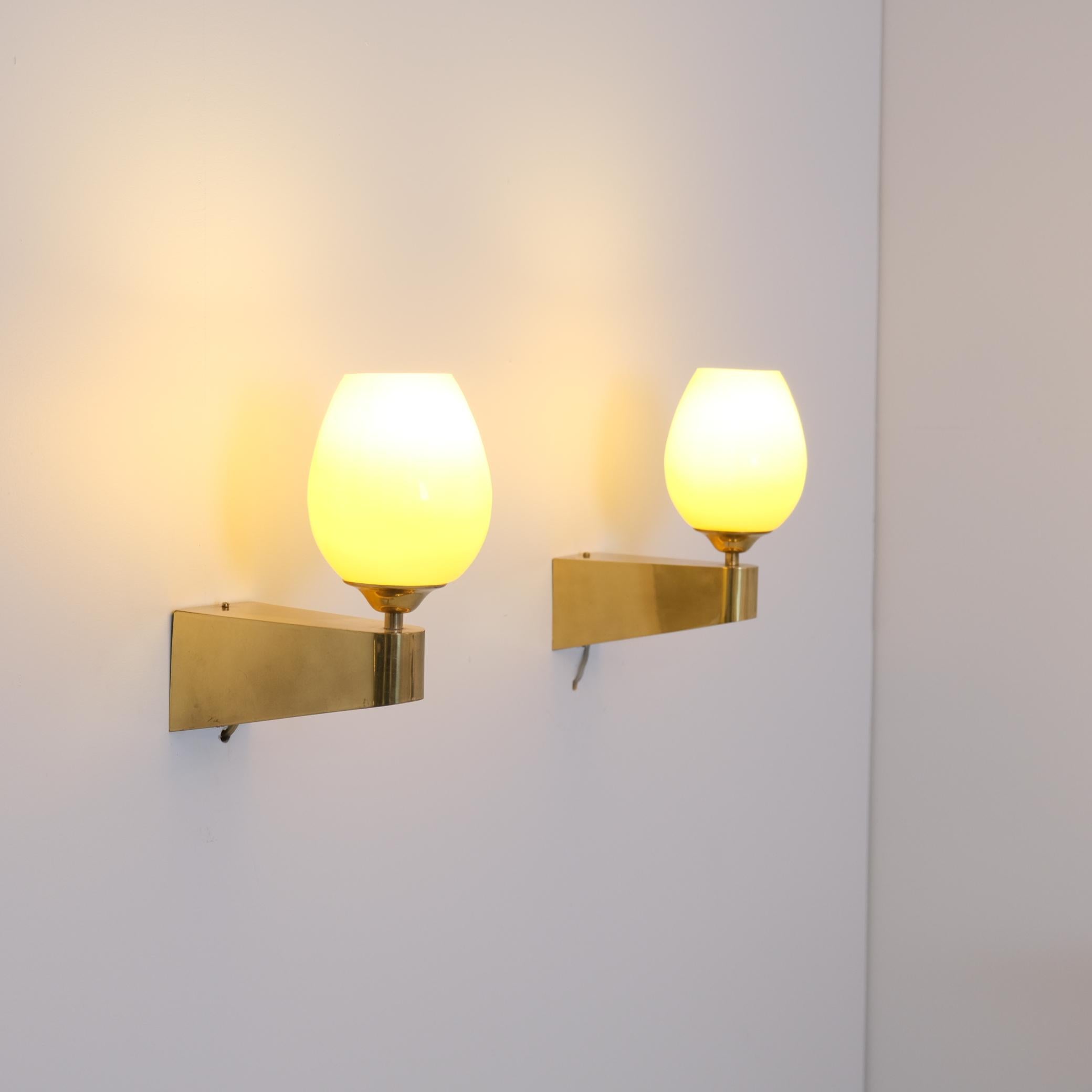 A nice pair of wall lamps in full brass, made by Itsu in Finland in the 1950s. Model EY 49. 

The lamps are minimalistic with a cubic design softened by curves and crowned with a hand blown glass shade. Absolute beauties. Both lamps are in good