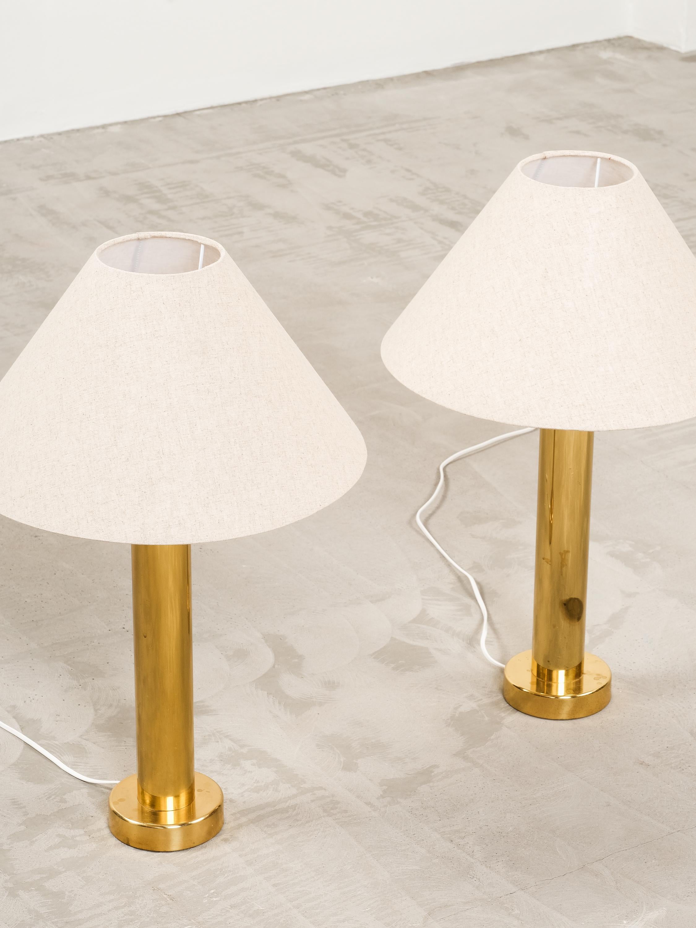 Pair of large mid-century Swedish brass table lamps made by Kosta Elarmatur in Sweden, 1960/70s.

These large and very elegant table lamps feature a tall brass stem and base, as well as a large cotton/linen mix shade. They feature a very clean and