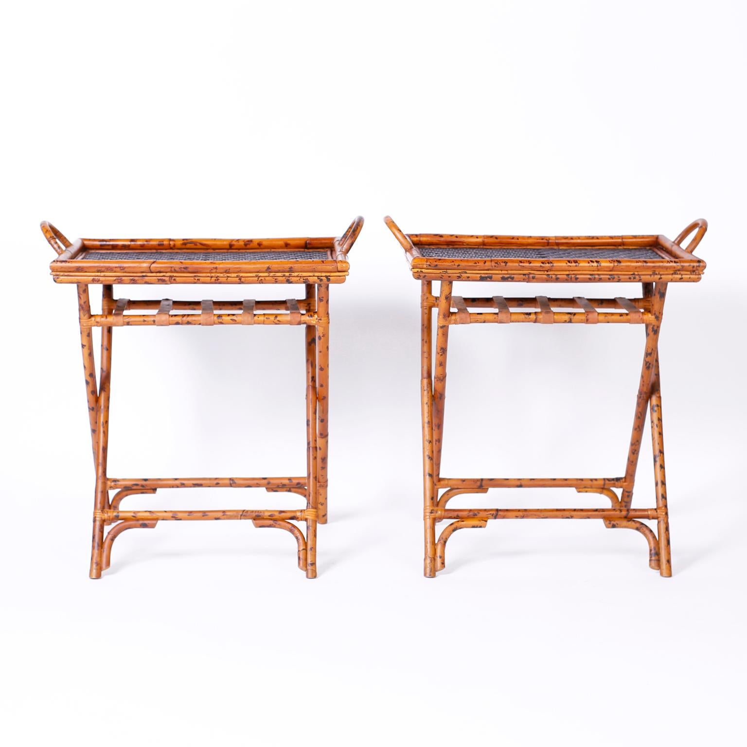Multi purpose pair of midcentury British colonial tray tables crafted in burnt bamboo with removable herring bone, woven reed or wicker tops, bent bamboo handles and folding X-form bases.