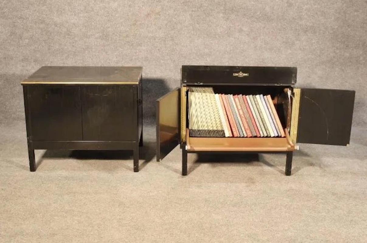 With a sleek ebonized exterior and brass accents and hardware, this pair of small mid-century cabinets by Music Minder is perfect for storing a record collection or adding organization to a space. Please confirm item location with seller (NY/NJ).