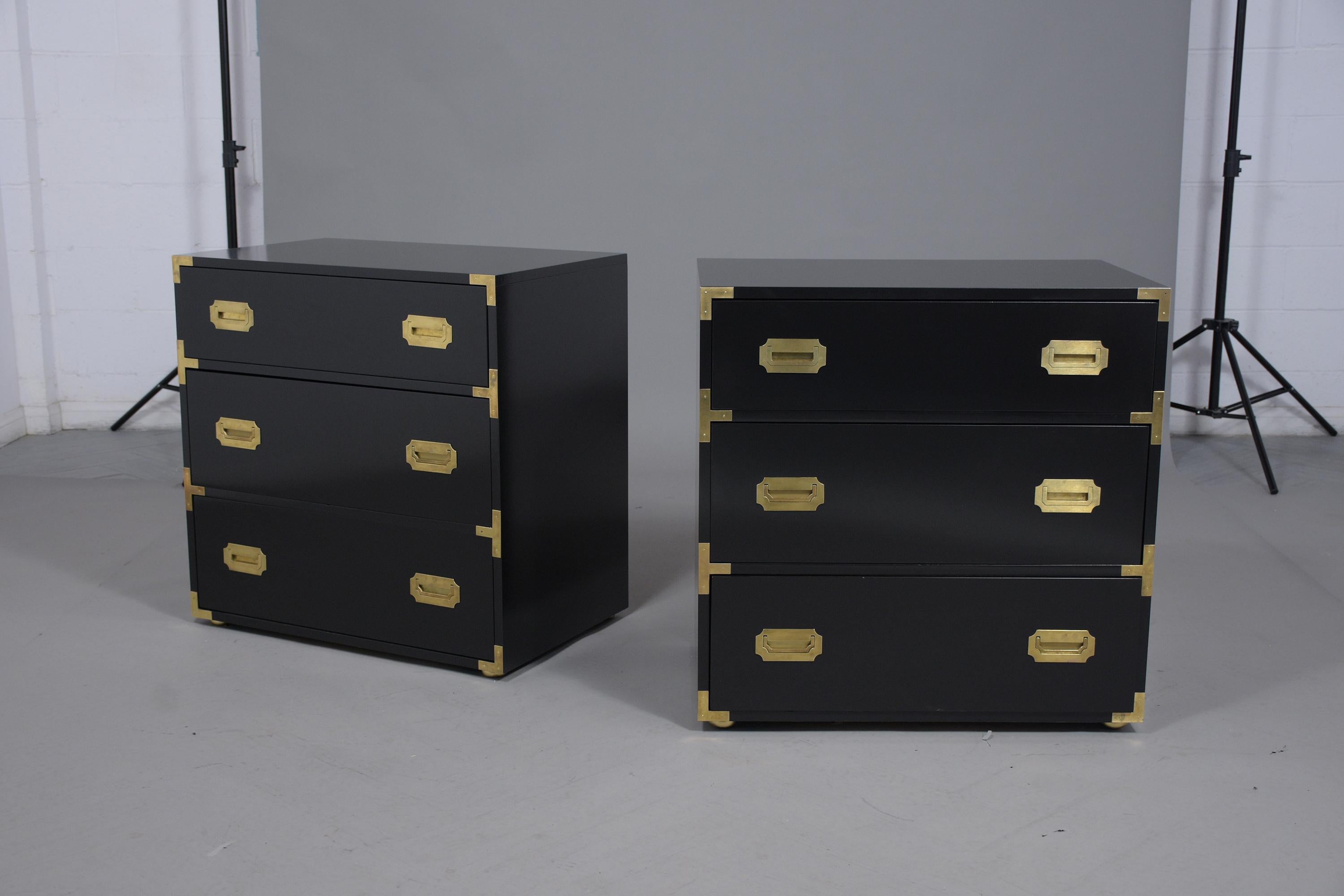 Elegant pair of vintage mid-century three-drawer dressers has been professionally restored and painted in rich black color with a lacquered finish. These fabulous dressers come with brass accents on all corners and have their original brass handles