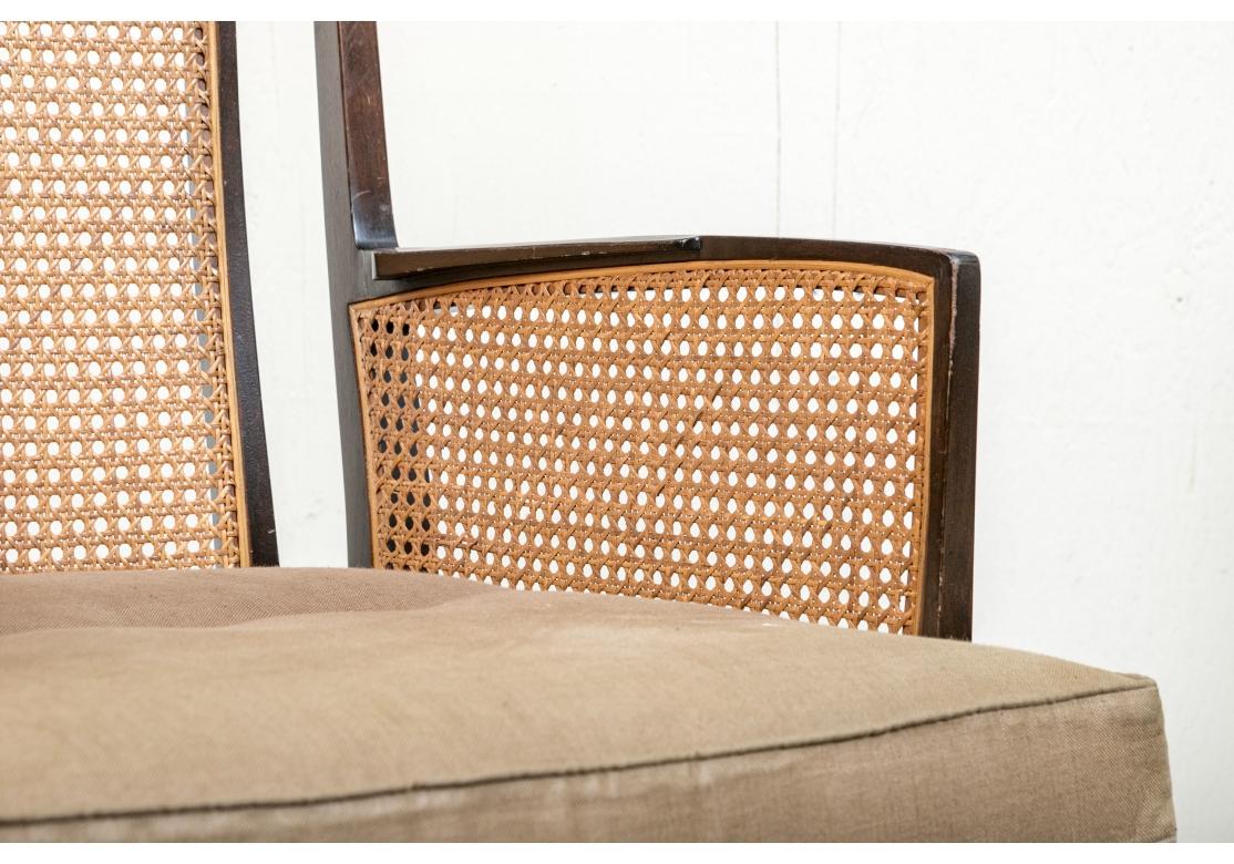 Pareja de elegantes sillones de época de mediados de siglo con respaldo y laterales de panel de caña. La Pareja exhibe toques de estilo asiático con marcos lacados en madera oscura y fina forma calada. Los Pares son de mayor escala y bastante