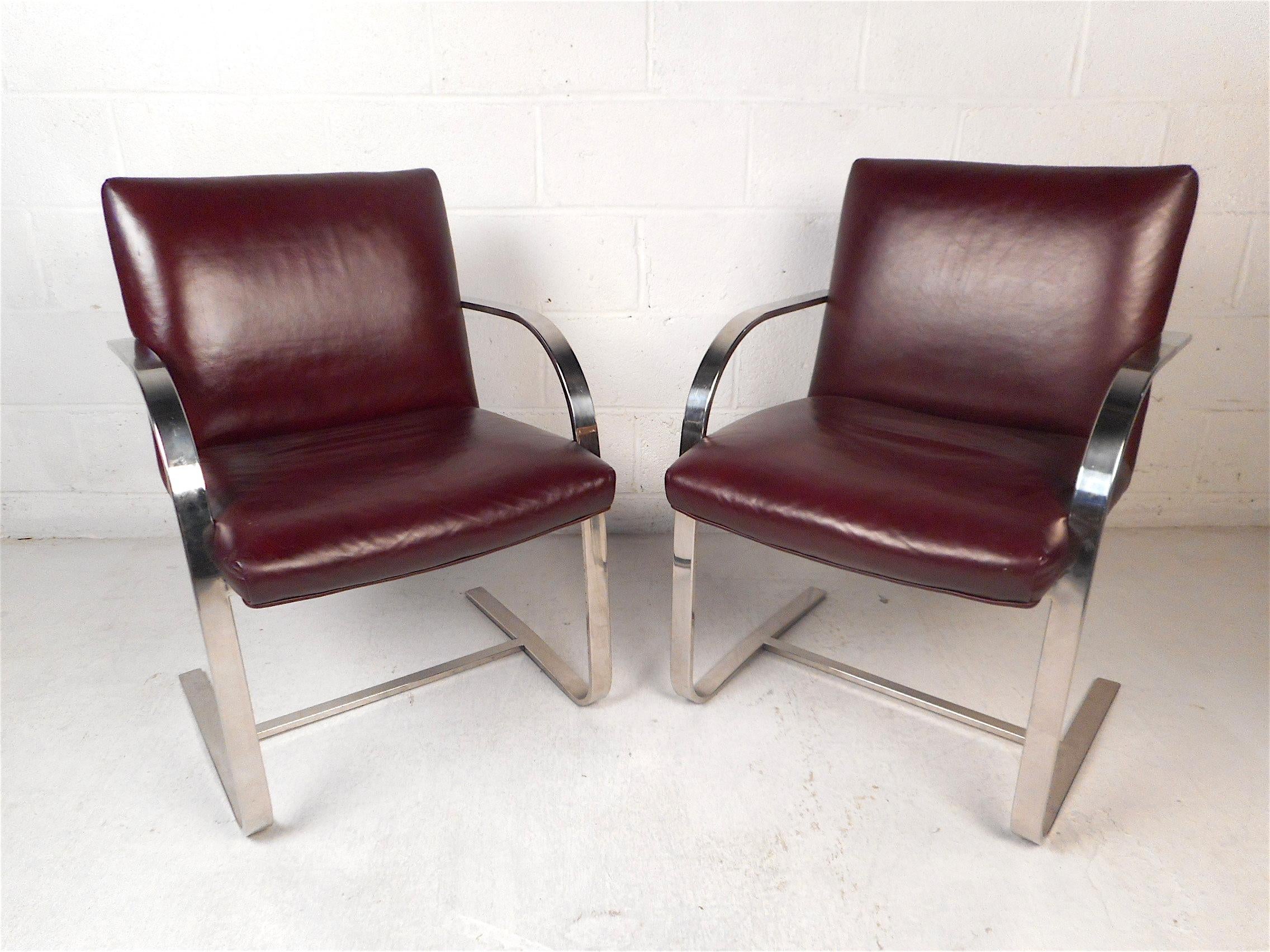 Stylish pair of mid-century armchairs. Sleek chrome frame with curved armrests leading into the cantilevered base supports. Covered in a vintage dark purple vinyl upholstery. Great pair sure to impress in any home, business, or office's modern