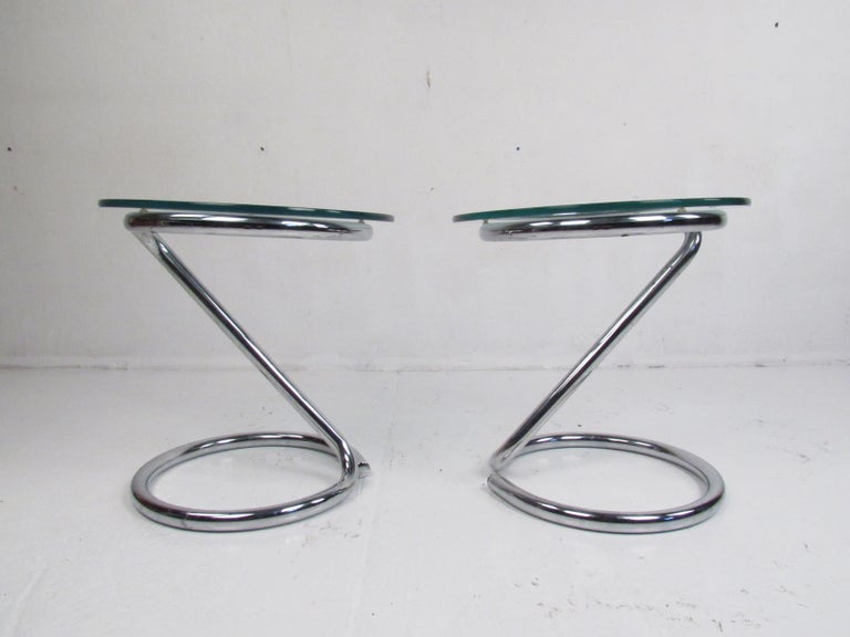 This stunning pair of vintage modern end tables boast a tubular chrome cantilever frame and a circular glass top. An unusual and stylish design that is sure to make a lasting impression in any modern interior. Please confirm item location (NY or NJ).