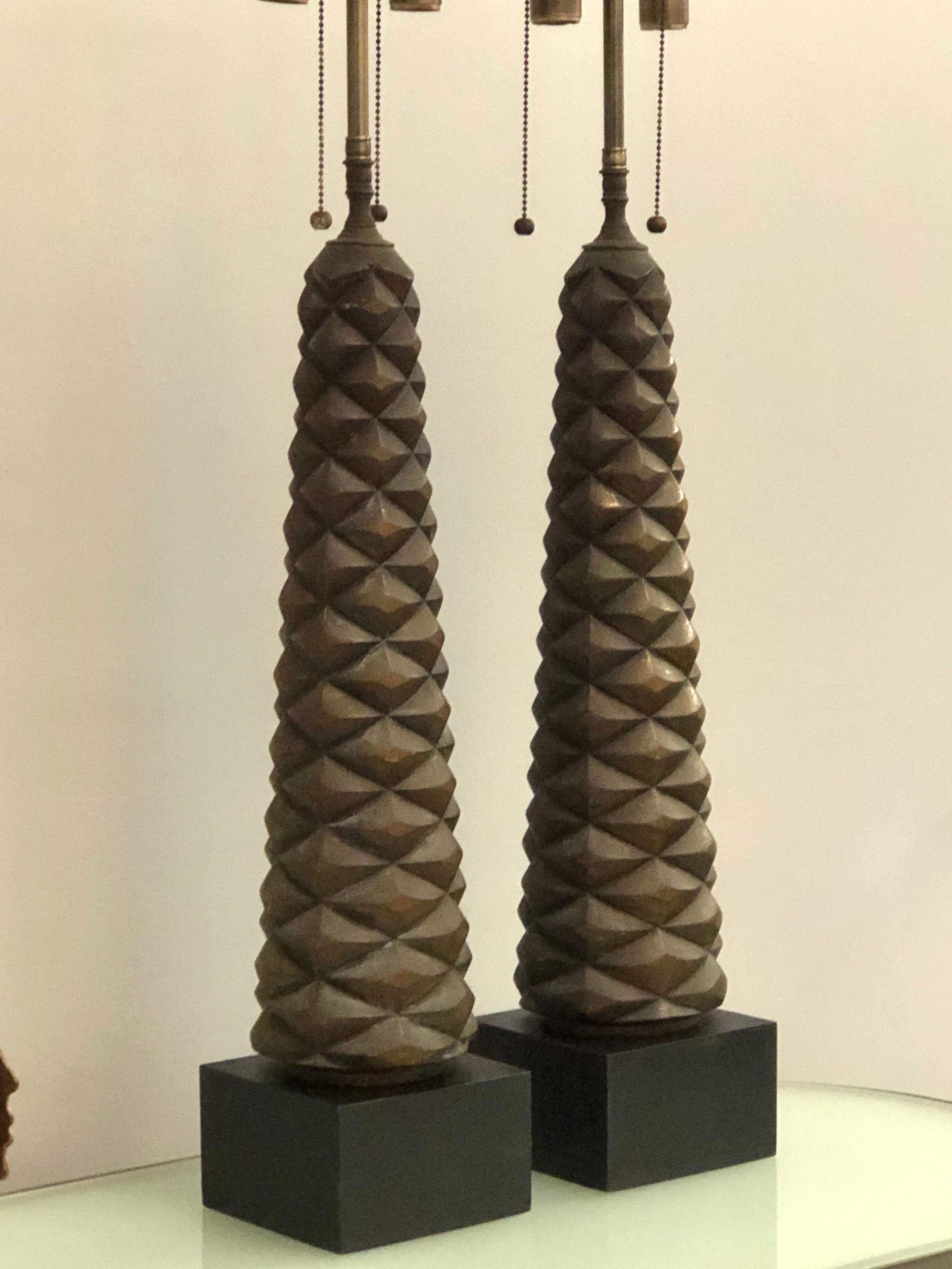 A pair of stunning table lamps. The base is carved in an almost geometric pattern with an organic flair that resembles the trunk of the date palm tree. They have a burnished gilt finish that has darken with age.