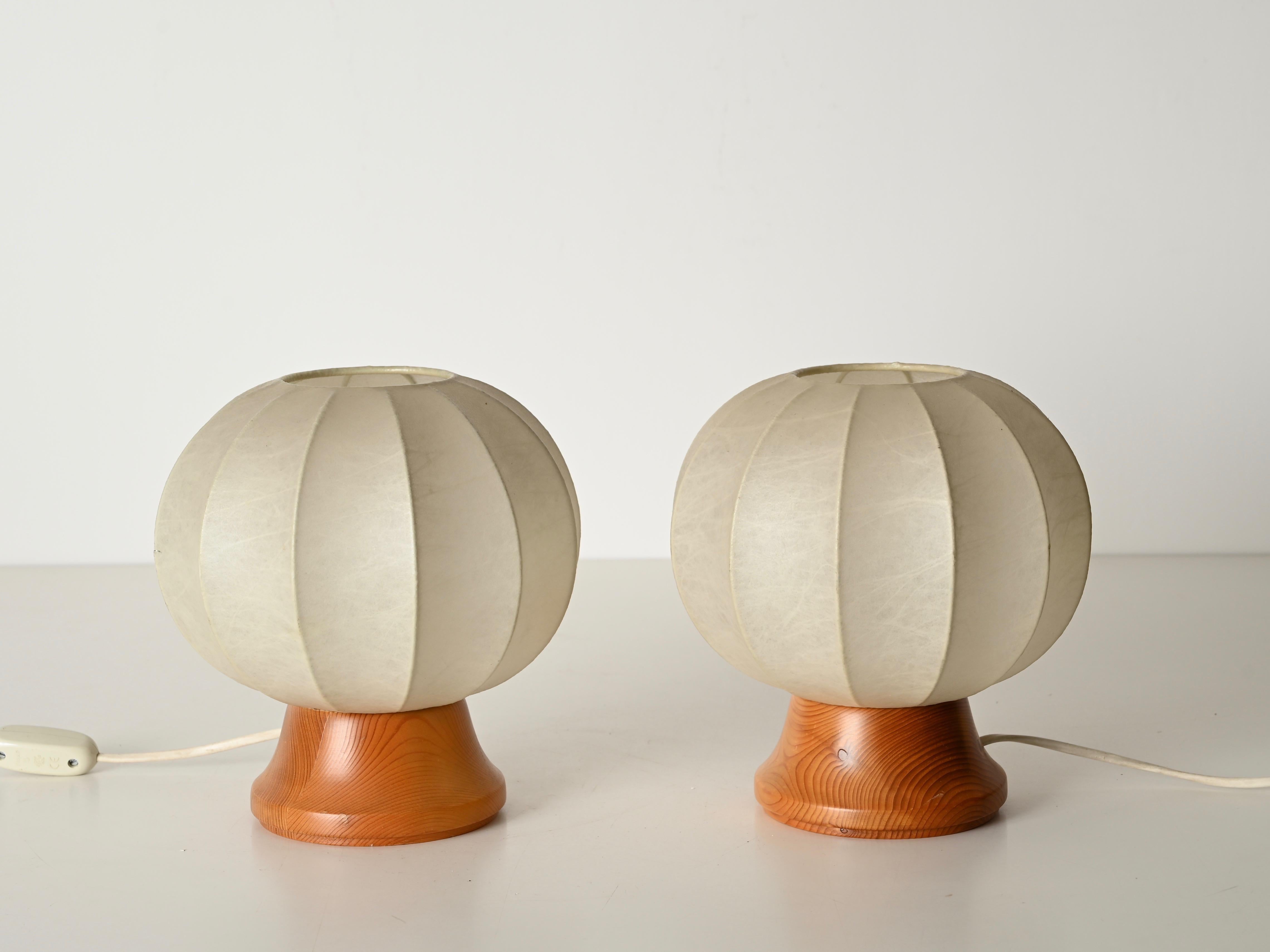 Merveilleuse paire de lampes de table cocon du milieu du siècle conçues par Castiglioni et produites en Italie dans les années 1970.  

Ces lampes de table élégantes ont une base ronde en bois de chêne complétée par un abat-jour beige 