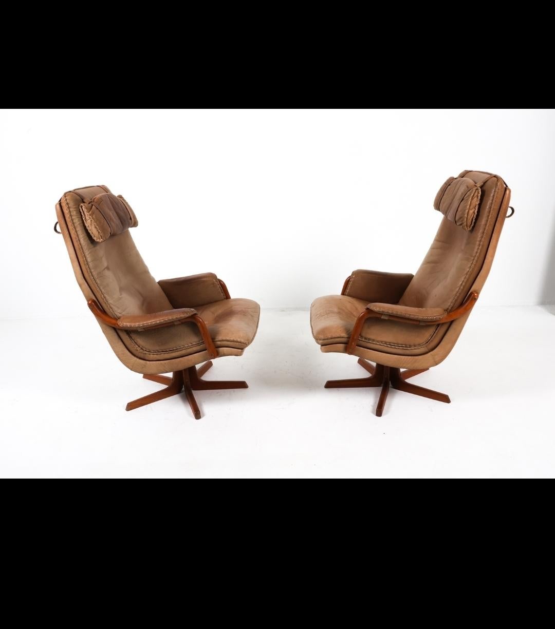 Ein perfekt patiniertes Paar Stühle aus Teakholz und Leder von Berg of Denmark. Diese Drehstühle sind lustig und bequem. In den 1970er Jahren entstanden, mit handgefertigten Peitschenstichkanten und einem Gürtel, der die Kopfkissen hält. Dieses
