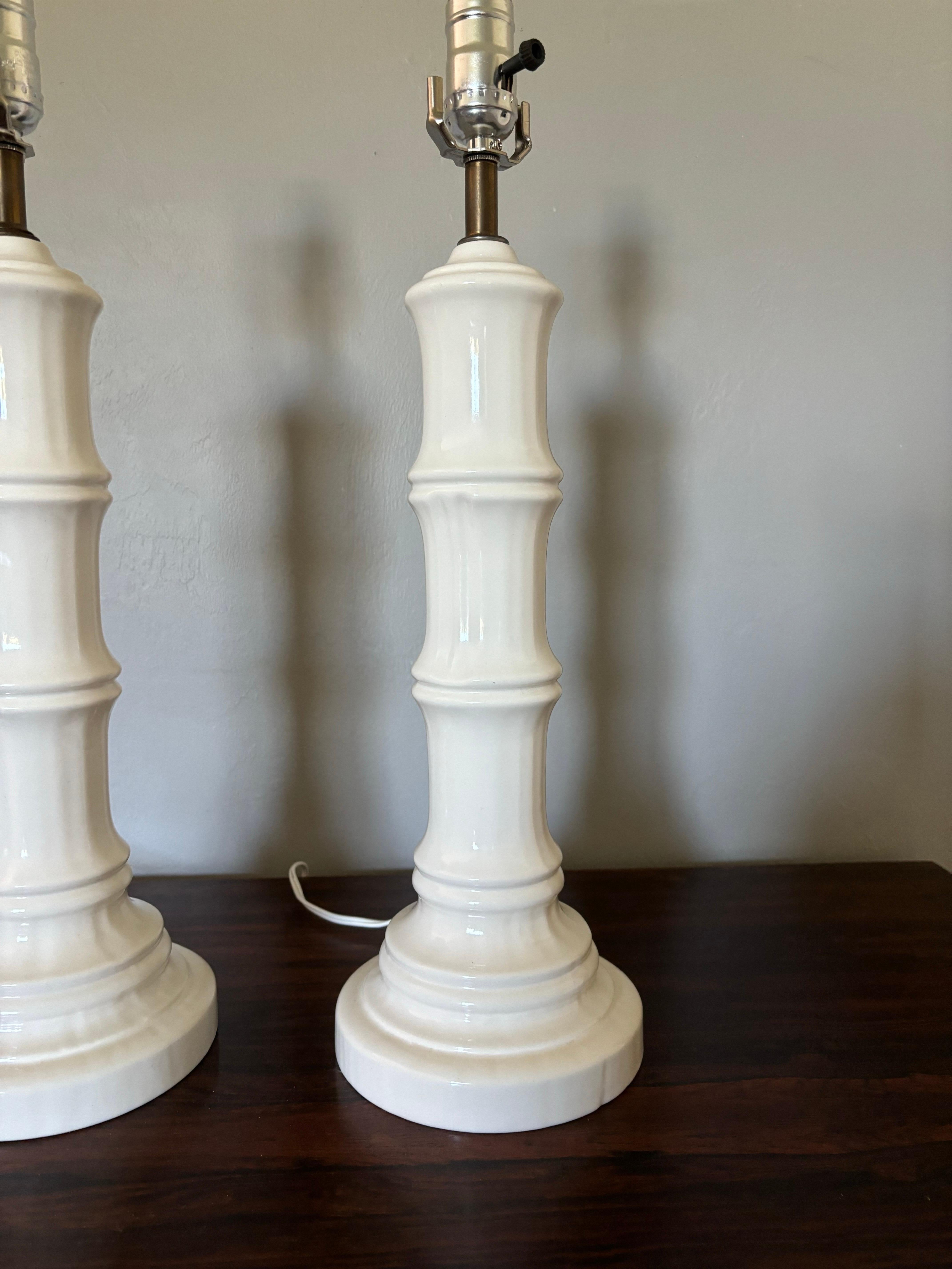 Excelente par de lámparas de sobremesa de bambú sintético de mediados de siglo. Con su acabado original de cristal esmaltado en blanco. Un diseño muy limpio con un toque caprichoso gracias al bambú de imitación. 

El cableado original funciona bien.