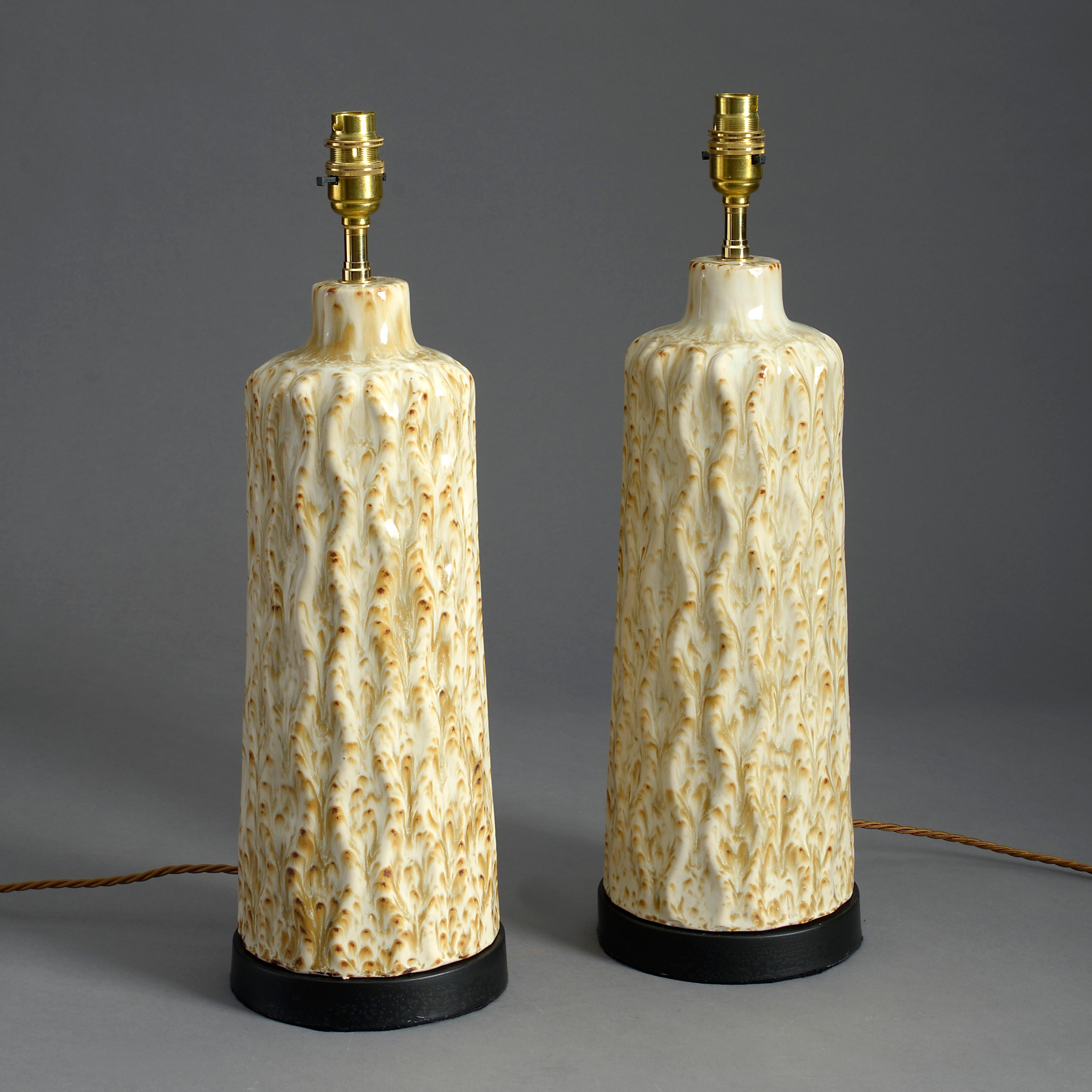 A pair of mid-twentieth century cream glazed ceramic lamps, with faux tree bark surfaces and set upon painted tole bases. 

Shades not included.