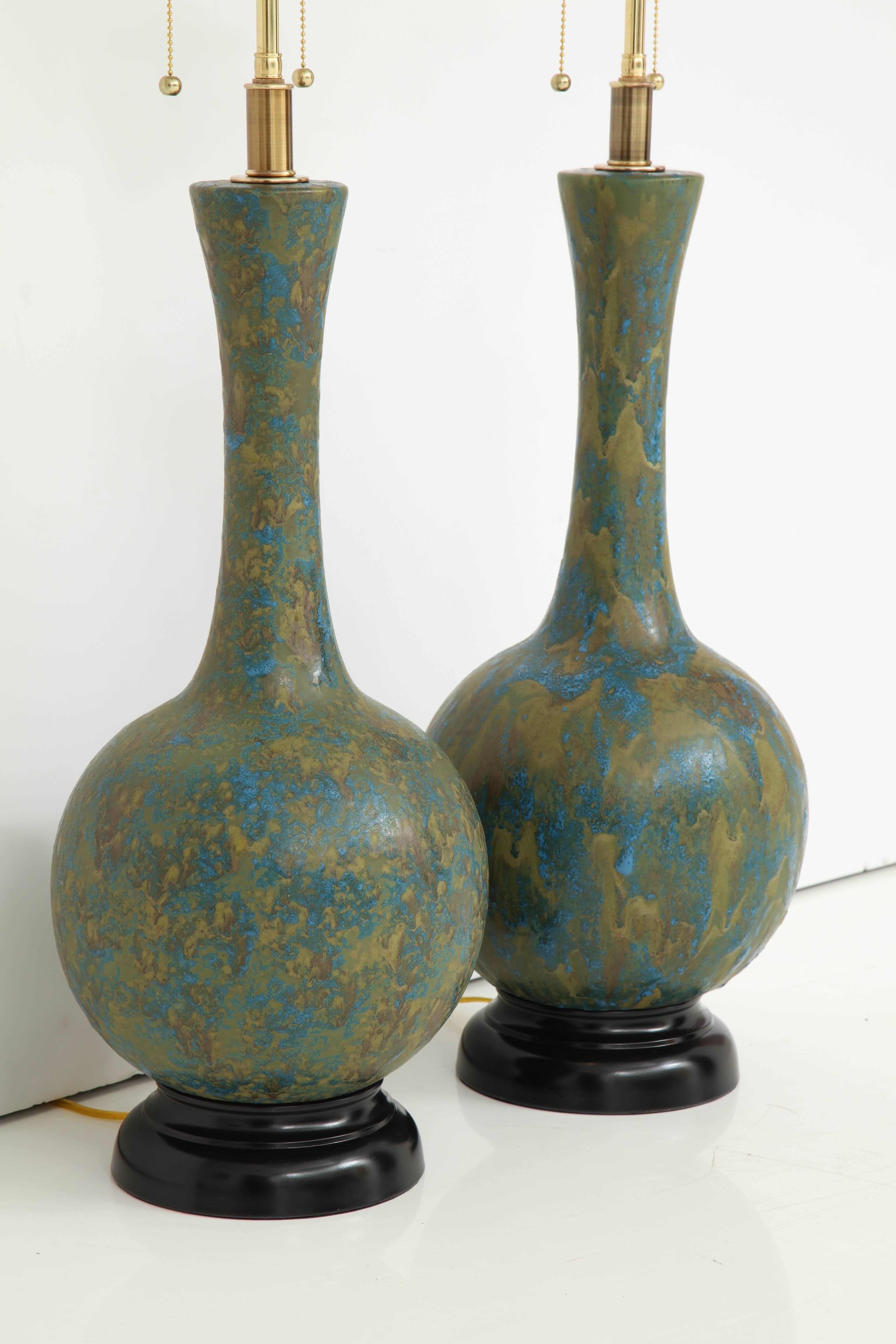 Pair of 1960s Italian Mid Century ceramic lamps with a textured glazed finish.
The lamps have been newly rewired for the US with polished Brass double clusters that take standard light bulbs.
The overall height of the lamps to the finial is 34.5