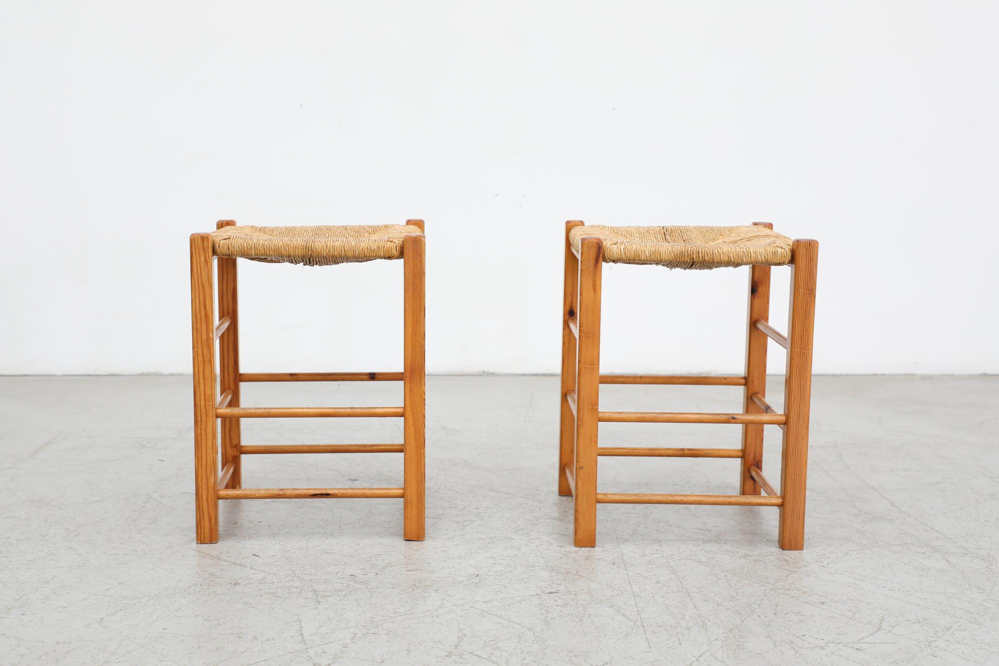 Pair of Charlotte Perriand style counter stools with woven rush seat and oak frame. In original condition with visible wear and may be have rush breakage. Wear is consistent with its age and use. Set Price. 