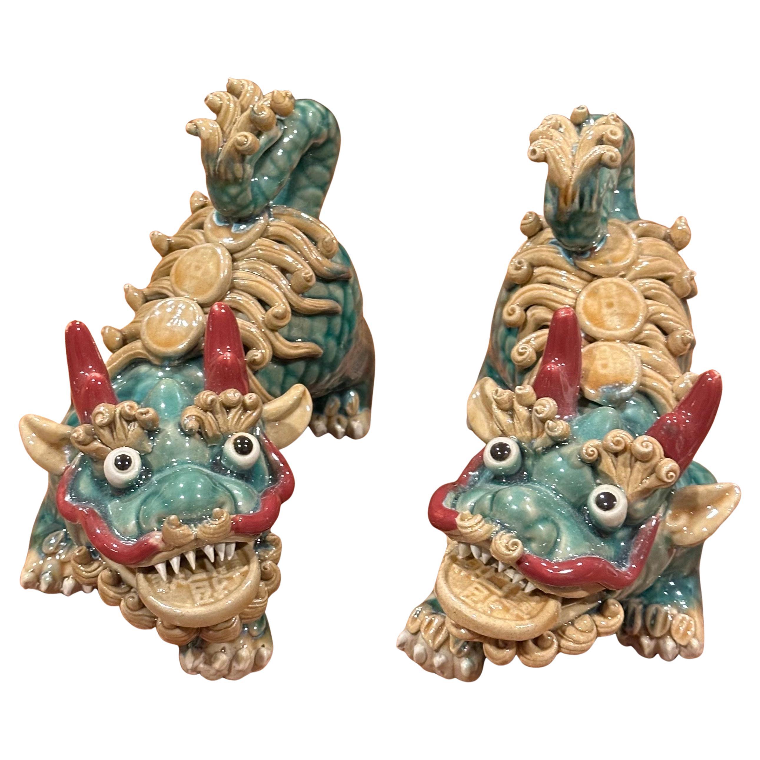 Coppia di cani da caccia in ceramica smaltata policroma della metà del secolo scorso, provenienti dalla Cina, circa 1950. Ogni cane tiene in bocca un medaglione di monete ed è caratterizzato da una splendida combinazione di colori: marrone, verde e