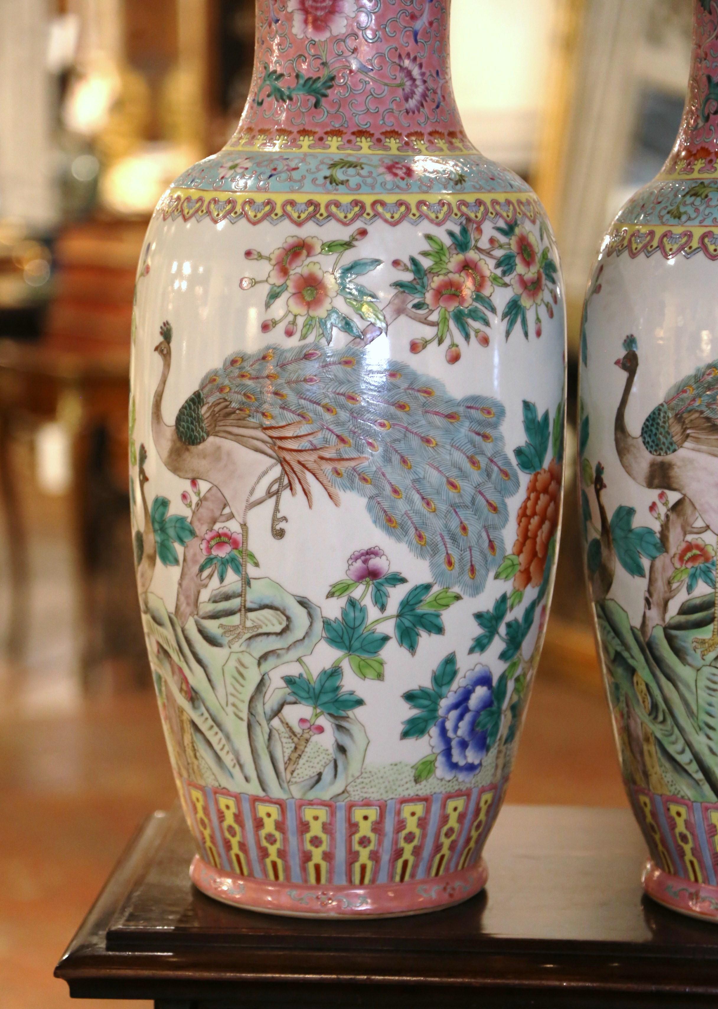 Diese eleganten, farbenfrohen Famille-Rose-Vasen wurden um 1950 in China hergestellt. Die großen, hoch aufragenden Gefäße haben einen ausgestellten Rand und einen konisch zulaufenden Körper. Jeder Körper ist mit lebhaften Blumen- und Pfauenmotiven