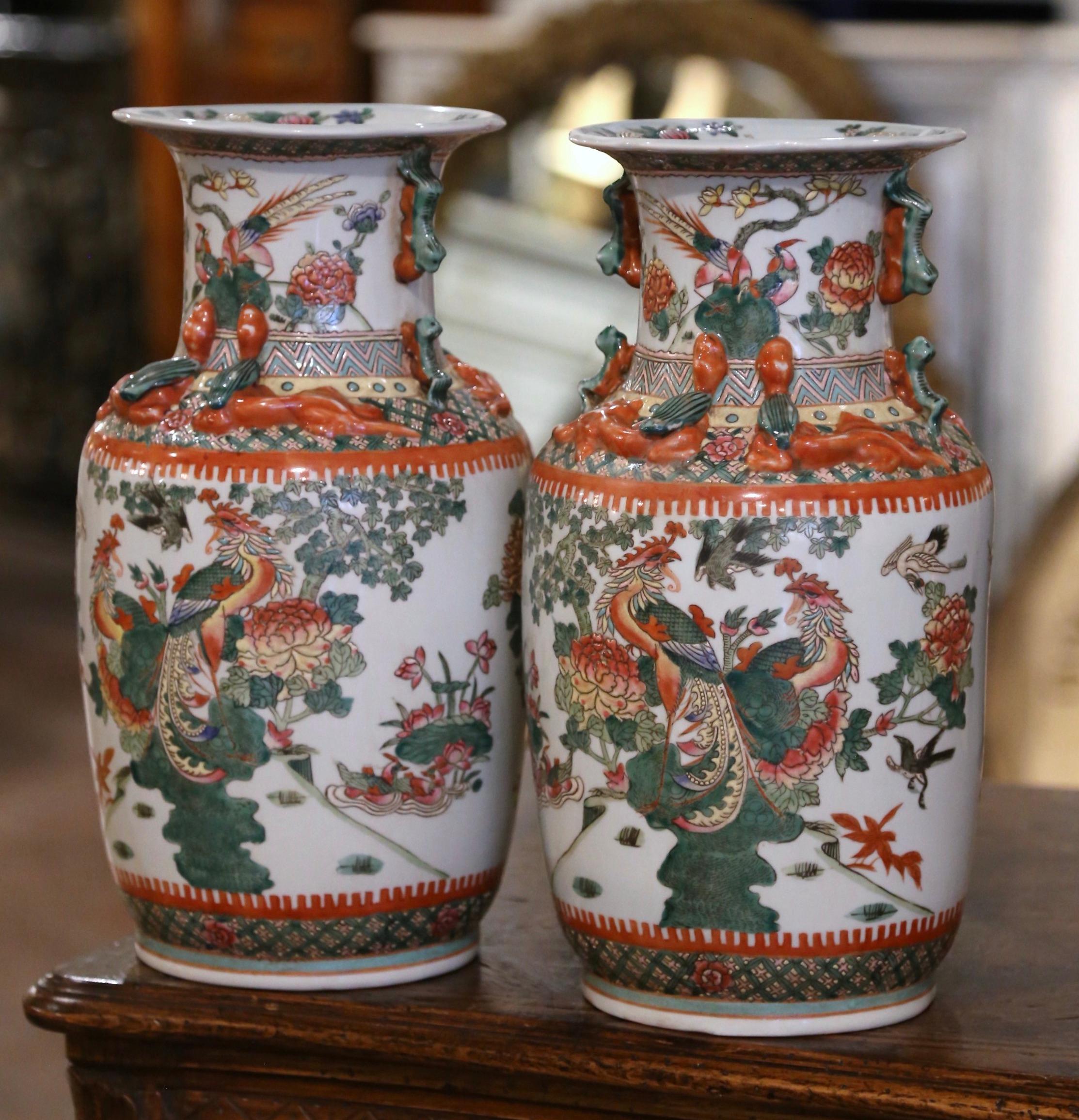 Decorate a table or a console with this pair of colorful antique porcelain vases. These elegant colorful vases were created in China circa 1950. The large vessels with flared rim and tapered body, are decorated with lizard and foo dog motifs around