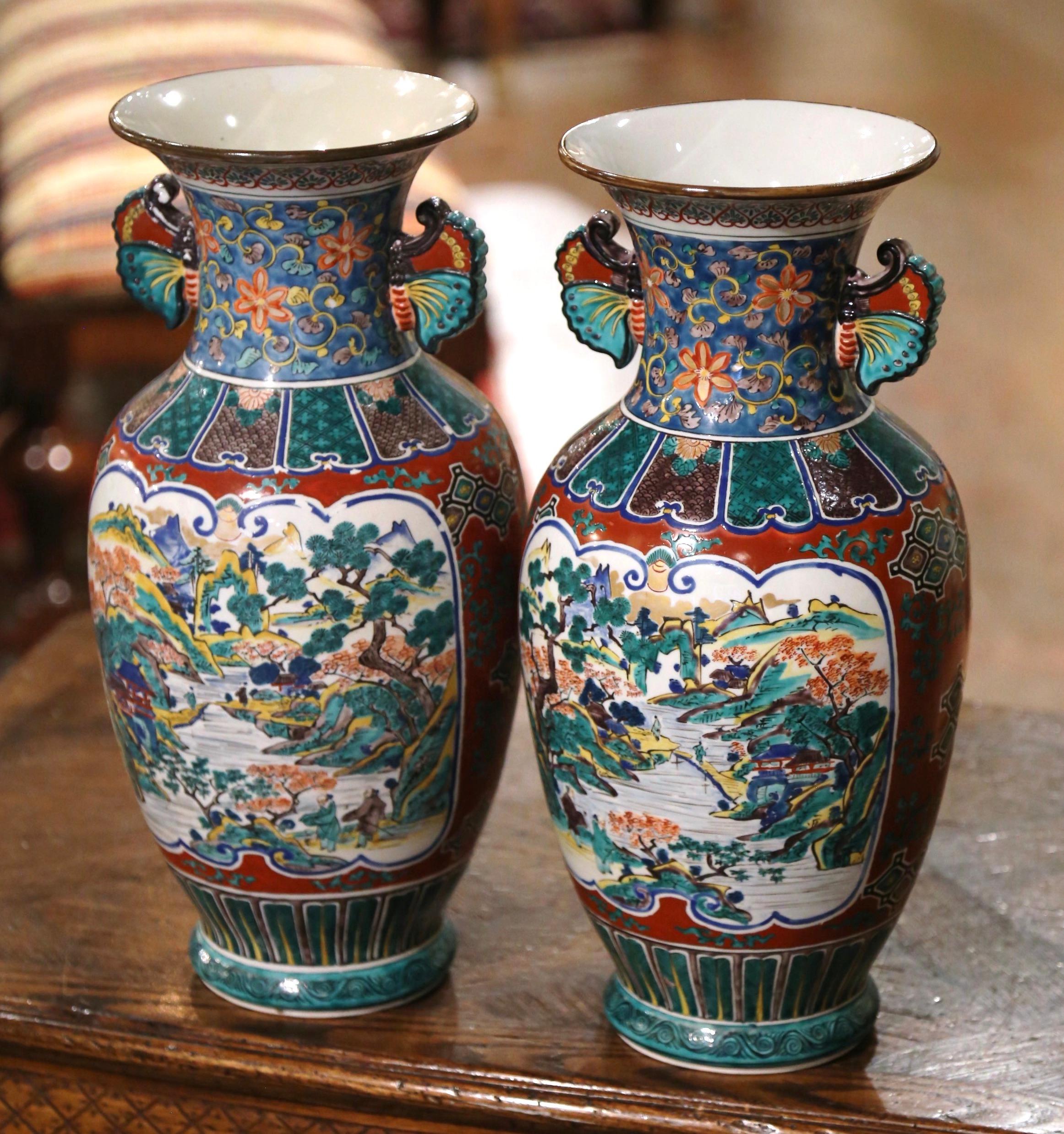 These elegant vases were created in China circa 1950. The large vessels made of porcelain, feature a tall and wide neck embellished by butterfly form handles on either side. Each vase is decorated with hand painted polychrome enameled flowers,
