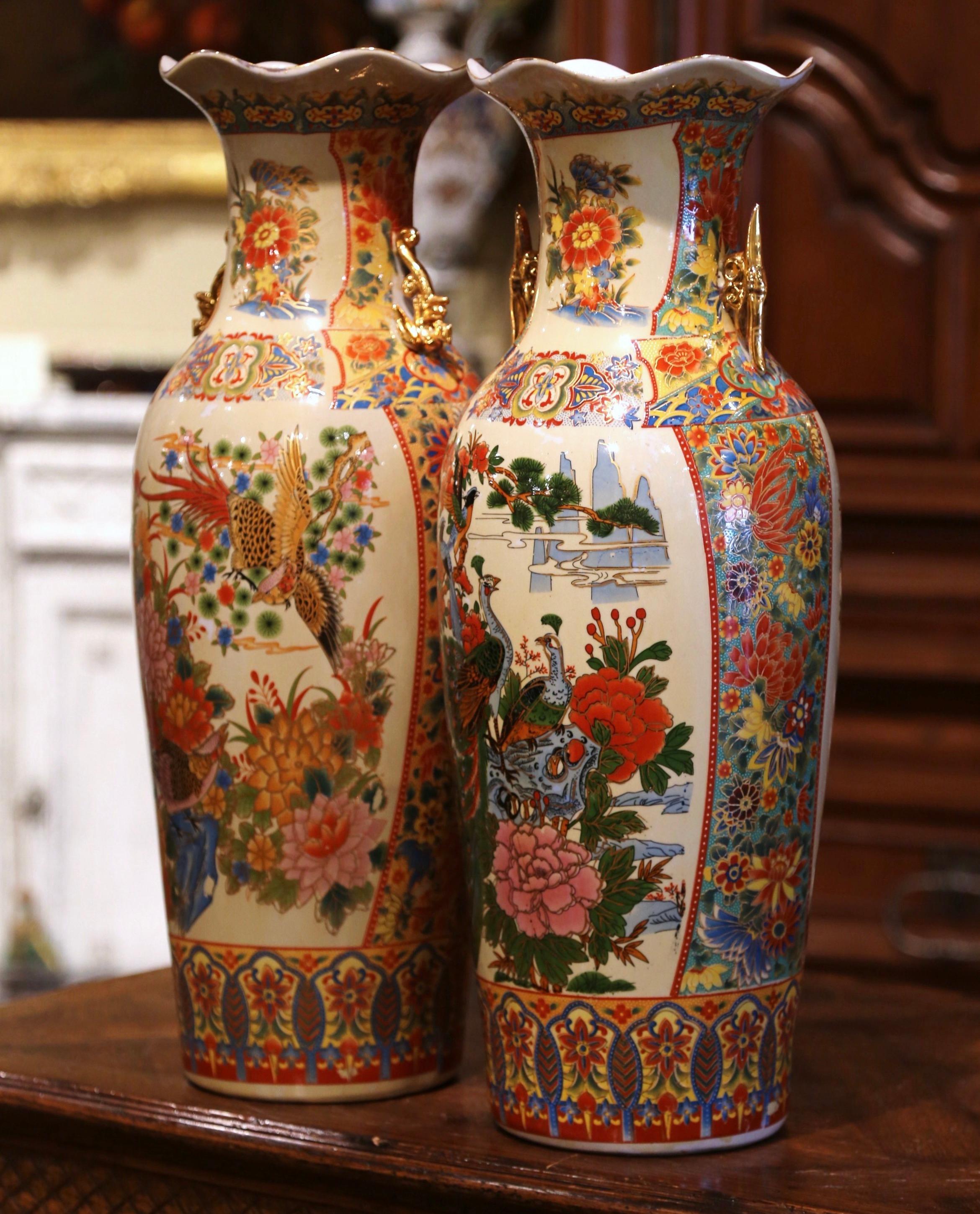 These elegant colorful vintage vases were created in China circa 1970; made of porcelain and embellished with gilt ruyi scepter handles, each tall vase with scalloped rim, is decorated with hand painted polychrome enameled flowers, and alternating