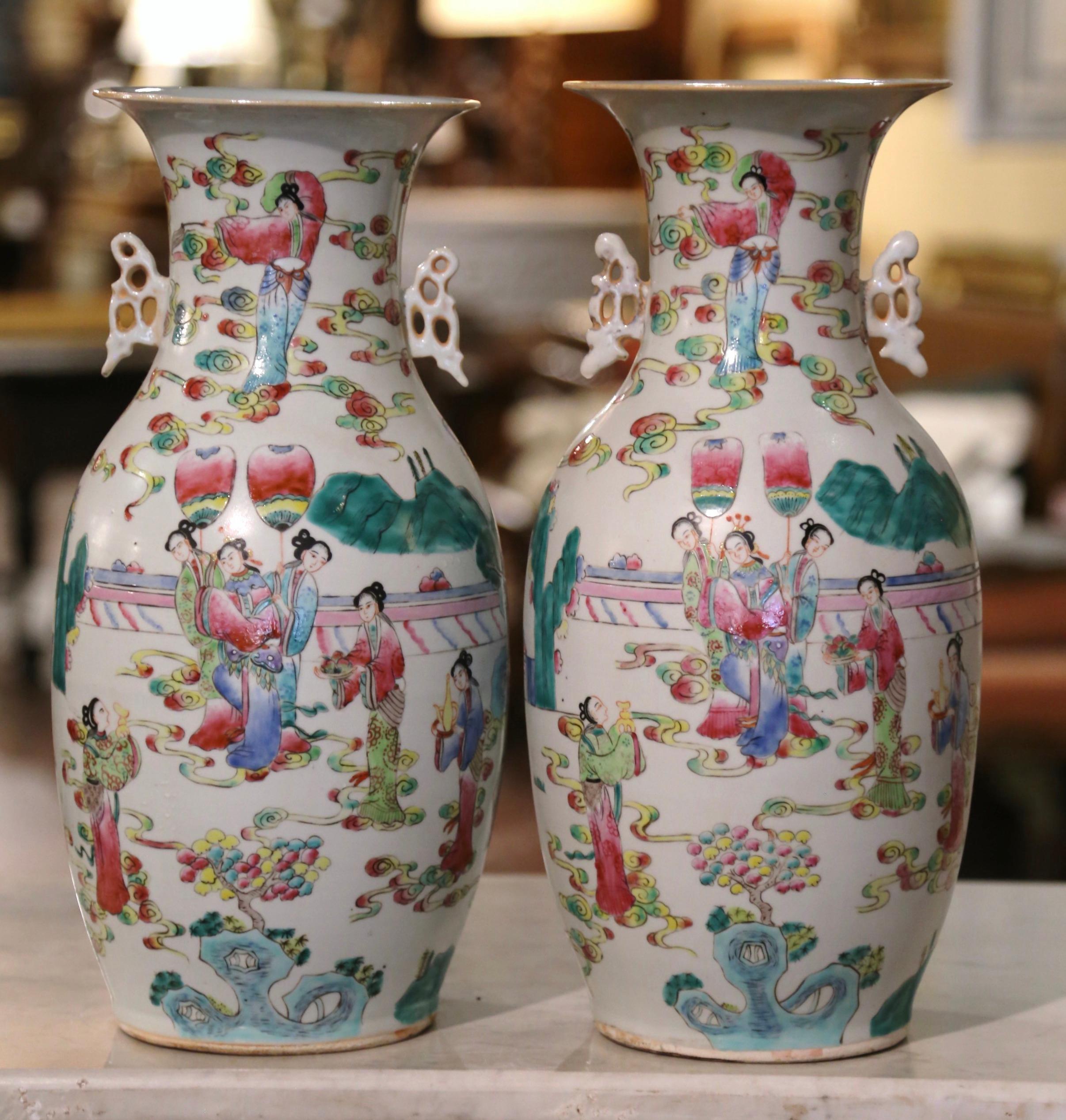 These elegant vases were created in China circa 1950. The large vessels made of porcelain, feature a flared rim over a tapered body embellished by butterfly form handles on either side. Each vase is decorated with hand painted polychrome enameled