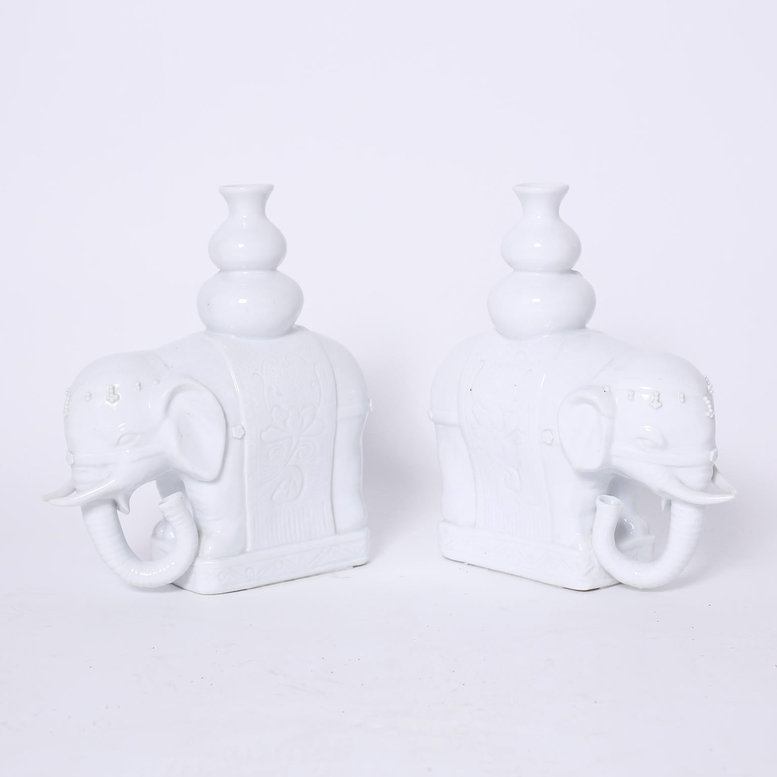 Intriguing pair of midcentury Chinese porcelain elephants with a white glaze carrying vases or vessels. Signed Maitland-Smith on the bottom.